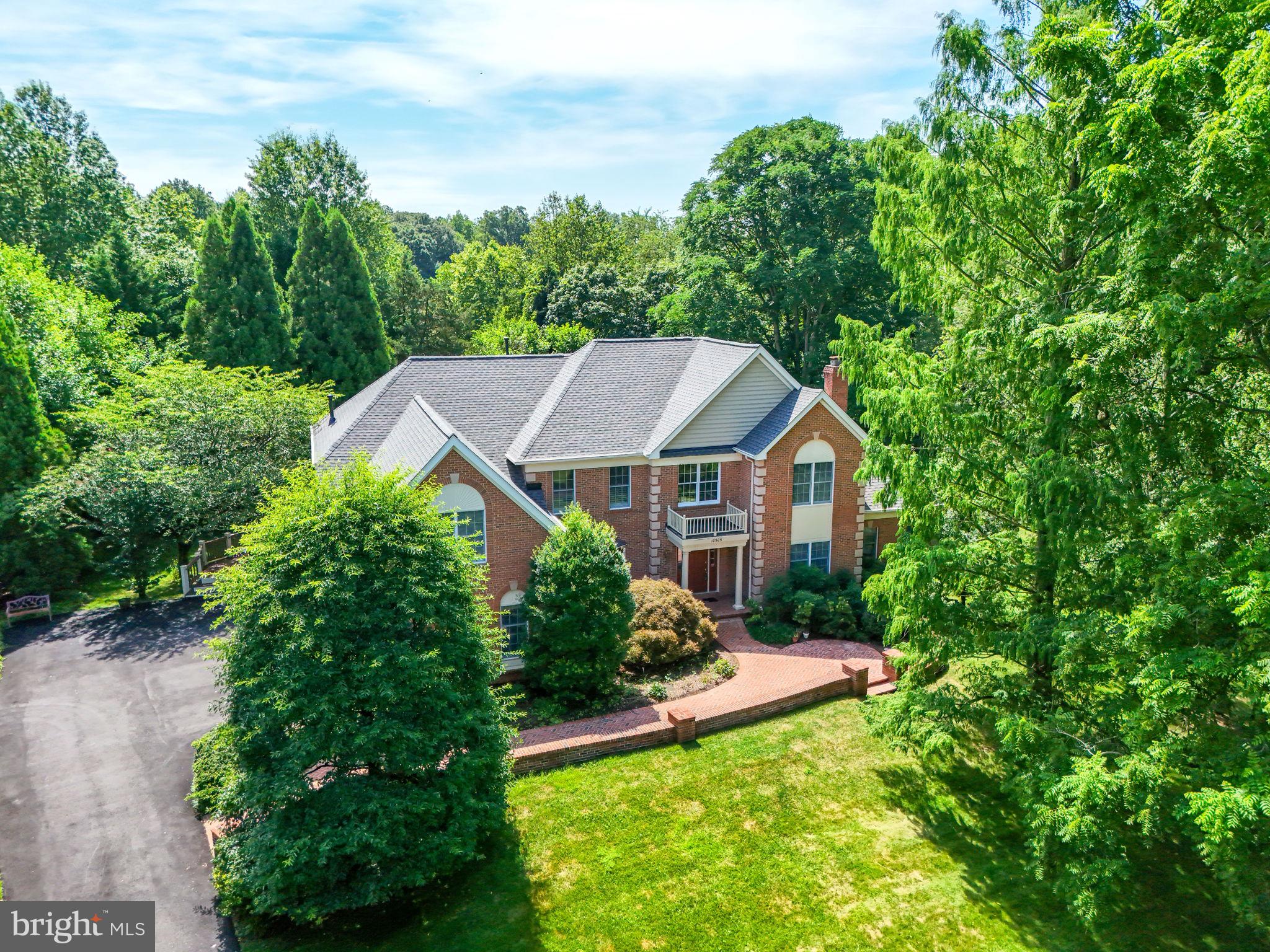 Welcome to an elegant executive home in the prestigious Estates at Great Falls Crossing, nestled on a serene private road and surrounded by lush common areas with tranquil pond views. This .75-acre property offers unmatched privacy, beauty, and sophistication. Step into the grand two-story foyer, where a chandelier on a mechanical hoist adds both elegance and convenience. The home features a split staircase, formal living room with fireplace, and a formal dining room perfect for entertaining. A breathtaking sunroom with vaulted ceilings and floor-to-ceiling windows flows seamlessly from the living room, offering panoramic views of nature. The gourmet kitchen is a chef’s dream—center island with gas cooktop, new wall oven and refrigerator, and a sunlit breakfast area with skylights. Adjacent, the family room boasts a vaulted ceiling and cozy gas fireplace, while a main-level office with built-ins provides a stylish workspace. The spacious mudroom and covered porch—featuring a coffered ceiling, ceiling fan, and gas line—complete the main level. Rich hardwood floors span the main level, enhancing the home’s warmth and elegance, while the sunroom offers a complementary tile finish suited to its bright, airy design. Upstairs, the flyover bridge offers a sweeping view of the family room below. The luxurious primary suite includes a tray ceiling, sitting area, three walk-in closets, and a spa-style bathroom with vaulted ceilings, skylights, soaking tub, shower, and dual vanities. Bedroom 2 enjoys its own ensuite bathroom, while Bedrooms 3 and 4 share access to the hall bathroom. The unfinished basement offers incredible potential—already outfitted with a rough-in for a full bathroom and ceiling height that can be finished to 9'. A spacious 3-car garage includes storage cabinets and shelving for ultimate organization. Enjoy extensive landscaping in the beautifully treed backyard, enhanced by the peace and privacy of the setting. Recent upgrades include a new roof (2025) and a full-house generator for added peace of mind. All this just minutes from Reston Town Center, Rt 7, Dulles Toll Road, Dulles Airport, and the Wiehle-Reston Metro Station.
