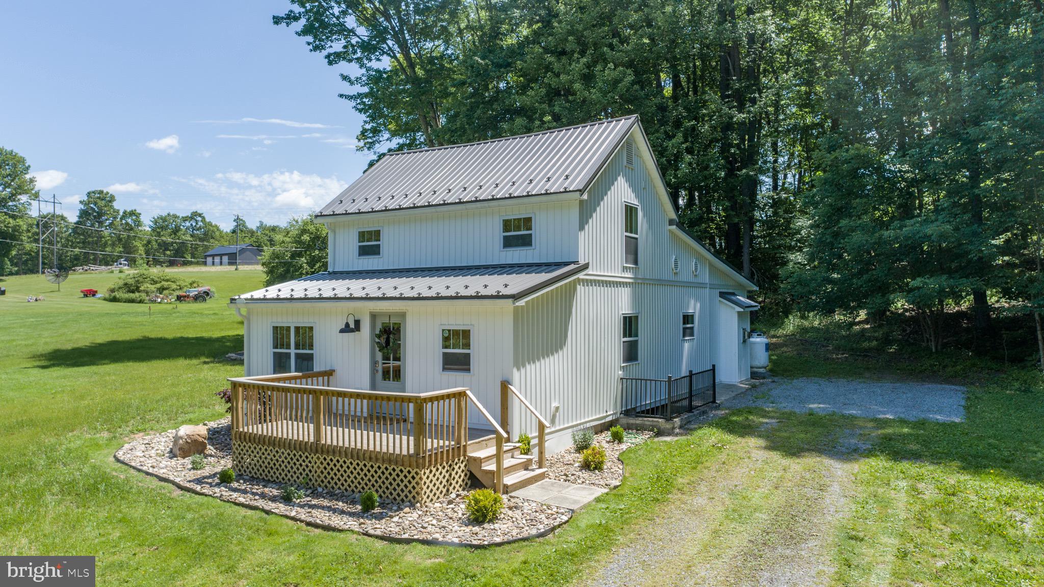 Completely updated and remodeled home just 5 minutes from Deep Creek Lake and Wisp ski resort! Located on 3+ acres, this rustic style home sits on a large, level yard with a setting of total peace and serenity. The entire home was completely renovated in 2023 - including a brand new metal roof, new windows, doors, flooring, decking, central a/c, and siding. The interior has a completely new floor plan - featuring a large, upper level primary bedroom suite with it's own private bath - a brand new kitchen with quartz counters, cabinets, and stainless appliances - brand new bathrooms - a new main level laundry room - and a large living room with gas fireplace. Enjoy those family and friends get-togethers outside on the side porch with a hot tub and fire pit. Established vacation rental. Turnkey with rustic and vacation home style decor throughout!