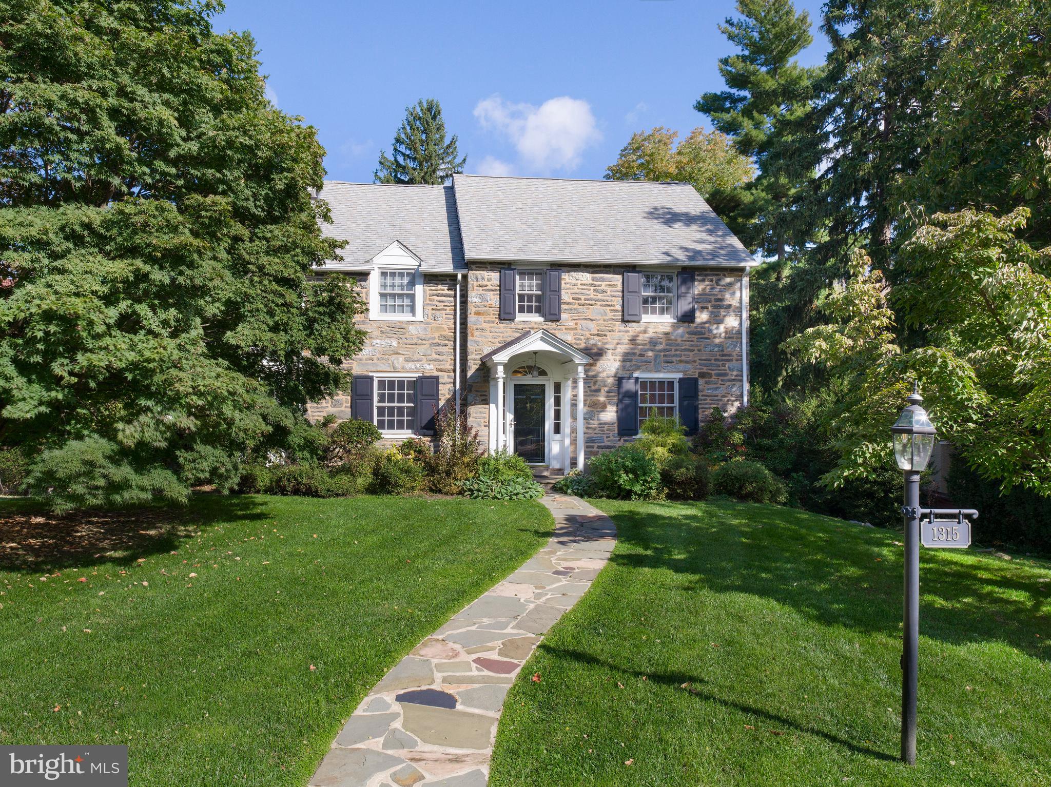 This stunning stone Colonial seamlessly blends classic charm with modern living, thanks to a thoughtful two-story expansion that enhanced both functionality and character. The addition introduced a spacious eat-in kitchen and great room, creating a natural gathering place filled with warmth and light. Upstairs, a luxurious primary suite was added, offering a private retreat with generous space and comfort. A new dormer enhances the roofline, bringing in additional light, while the expansion also included a garage, providing both convenience and practicality.
Designed for both everyday living and effortless entertaining, this home features an open, flexible layout that easily accommodates everything from quiet moments to large gatherings. The chef’s kitchen is a standout, with two ovens, a six-burner cooktop, two dishwashers, and two sinks—ideal for both entertaining and a kosher kitchen. Over the years, this home has hosted events ranging from small dinners to lively celebrations with up to seventy-five guests, creating an atmosphere of warmth and connection.
The outdoor spaces are equally impressive. A large deck with Ipe Wood Decking sits high above the backyard, offering stunning views and the perfect spot for morning coffee or quiet evenings. The sprawling yard features a thriving garden, producing fresh tomatoes, zucchini, kale, and herbs all summer long. An outdoor fire pit has been the setting for countless nights of s’mores and laughter, bringing loved ones and friends together under the stars.
Inside, the home is designed for both shared experiences and personal retreat. The sunroom, porch office, and multiple living spaces provide the perfect balance of togetherness and privacy. Spacious bedrooms offer comfort and generous closet space, while the primary bathroom features radiant heat floors for a touch of luxury. The home’s stone construction naturally retains warmth in the winter and stays cool in the summer, enhancing both comfort and efficiency. A key feature is the dry basement, which has remained completely dry through every season.
Set on one of the largest double lots in the area, this home offers a rare combination of space and privacy in a highly sought-after neighborhood. The surrounding community is vibrant and welcoming, with a beloved annual block party bringing neighbors together. Its location is unbeatable, just moments from Whole Foods, Suburban Square, top-rated schools, parks, and easy access to SEPTA’s Regional Rail and High-Speed Line.