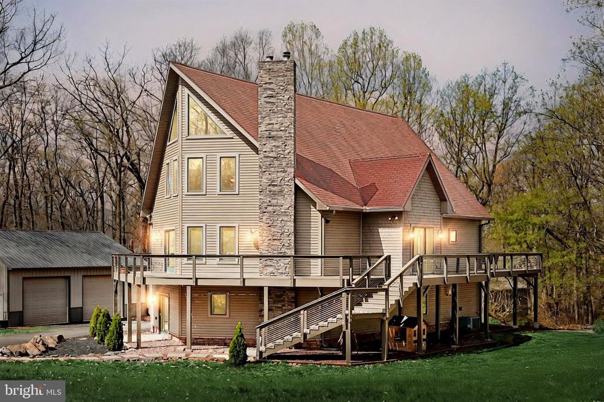 This is no ordinary home! Welcome to your own private getaway tucked away on 2+ acres, with an absolutely stunning 3 bed, 2.5 bath contemporary home that feels like a ski lodge in the woods, a fantastic 960 sq. ft. pole building built in 2021 with oversized doors and electric for all your cars, tools, toys and hobbies, plus additional equipment garage/shed! The main entry of the home impresses with 2-story foyer and stone accent walls opening into a vast, naturally lit main level boasting Brazilian hardwood floors, a great room with vaulted ceilings, stone mantel and wood/coal stove, walls of windows, sliding door to the Trex wrap-around deck built in 2022 and stone archways to the kitchen and dining room areas. Handsome finishes and fixtures create a dream gourmet kitchen equipped with built-in wall oven and microwave, gas cook-top range and huge center island with counter bar flowing smoothly into the open dining room  and adjacent laundry room with pantry storage. The sun room provides lovely views of the woods and grounds, access to the deck, and a perfect flex space for cozy relaxation, work or play. Spiral stairs lead up to an expansive primary suite with balcony overlook of the great room, Brazilian hardwood floors, two huge closets, and en-suite bath made to pamper with double vanity, jetted tub, oversized glass and tile shower, and two commodes! Downstairs engineered hardwood floors enhance two large bedrooms, and a family room with wet bar or kitchenette, slider to the patio and second wood stove with stone mantel. A second decadent full bath with soaking tub and walk-in shower complete this lovely home. Outside, the big level yard has lots of room to play and explore, surrounded by woods and nature. The recently constructed pole building is a fantastic garage or workspace with 2 high clearance overhead doors that can easily accommodate your RV, large vehicles and more, supplemented by a second garage/shed and large paved driveway with ample parking. You name it, this home has it all! Don't miss your chance to own this one-of-a-kind retreat, secluded but not isolated from the world, only minutes away from local shopping, dining and more!