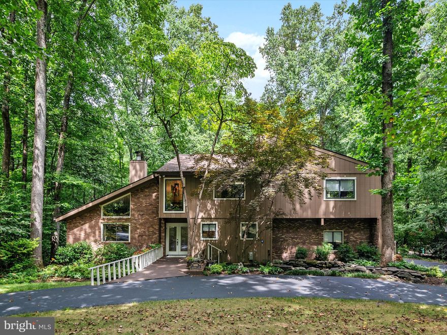 Set on 2 private acres in the heart of Annapolis, this contemporary 4-bedroom, 2.5-bath home offers a rare blend of privacy, modern comfort, and unbeatable location. Just minutes from Routes 50 and 97, you can enjoy an easy commute to Washington, D.C., Baltimore, and beyond—while still being close to downtown Annapolis’ waterfront dining, boutique shopping, and historic charm. The circular driveway sets the tone for welcoming gatherings, while the fully fenced yard is perfect for pets, play, and entertaining. Two storage sheds are included—one oversized, fully insulated, with electricity and a heat source—making it an ideal workshop, hobby space, or year-round studio.
Inside, the home greets you with an airy, light-filled living room centered around a dramatic two-story wood-burning fireplace. This architectural feature beautifully defines the living space from the adjacent dining area, creating a warm and inviting flow. The spacious eat-in kitchen offers stainless steel appliances, generous counter space, and a casual dining area—perfect for everyday meals or weekend brunch. Just off the kitchen, the family room opens to both a sunny wood deck and an enclosed sunroom, providing year-round enjoyment of the property’s natural surroundings.

Upstairs, each bedroom is a retreat in its own right, featuring high slanted ceilings and walk-in closets. The primary suite includes a private deck for morning coffee or evening stargazing, a walk-in closet, and an ensuite bath with a shower stall. The second bedroom has been converted into a stunning home office/library with gorgeous custom wooden bookcases, perfect for work or study. The third bedroom is beautifully updated and bathed in natural light, while the fourth offers flexibility as a guest room, nursery, or additional office. A newly remodeled shared bathroom combines style and function with modern finishes.

This home is more than just a place to live—it’s a lifestyle. Whether you’re hosting friends on the deck, enjoying quiet evenings by the fire, or heading into Annapolis for waterfront dining, you’ll love the combination of space, privacy, and proximity to everything.