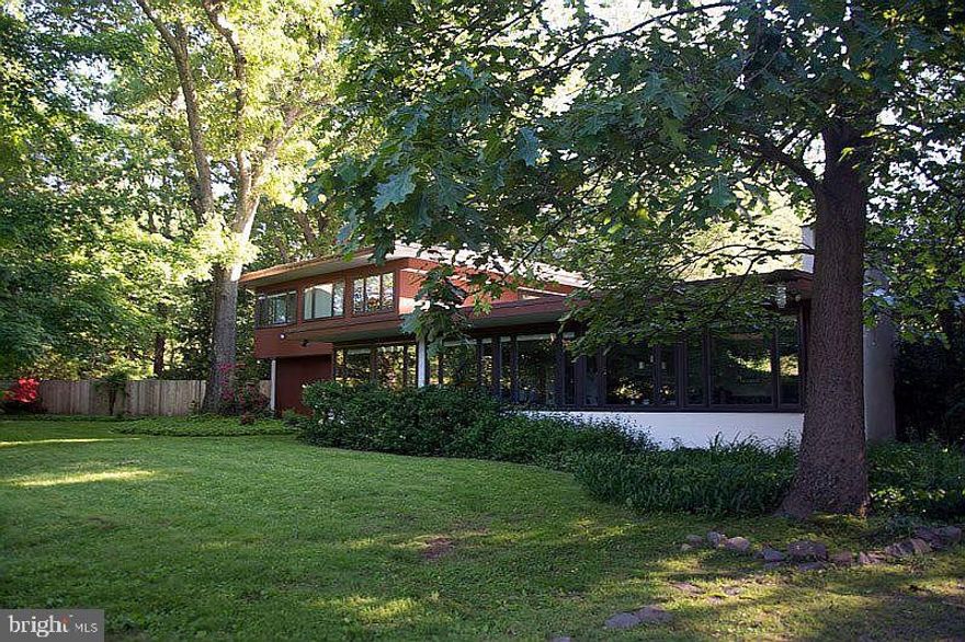 
Step into a world of architectural distinction at 1112 General St. Clair in Washington Crossing, PA 18977. This refined 5-bedroom, 3 and 1 1/2 -bath residence is a rare offering—an authentic Thaddeus Longstreth original custom-built home that artfully preserves its mid-century integrity while embracing thoughtful modern upgrades.
Perfectly positioned directly across from Washington Crossing Historic Park and the lagoon, you are literally steps from nature. Walk out your front door and into miles of scenic canal towpath, protected parkland, and enjoy a quick stroll to Washington Crossing Village and the Delaware River. For the discerning nature lover who values privacy, history, and design, this setting is simply unmatched. This is a one-of-a-kind opportunity to live, work, or play in one of the most beautiful and historic settings in Bucks County. Thaddeus Longstreth’s original renderings of this home are located in the  Architectural Archives Of the University Of Pennsylvania Thaddeus Longstreth Collection. 009.4.009.115-116,009.693  We are awaiting the file and will upload it as soon as we receive it.
The thoughtfully designed layout features three main-level bedrooms and two full baths, ideal for guests, flexible living arrangements, or convenient first-floor accommodations. Additionally, the main level features wall-to-wall windows, perfect for abundant sunlight and stunning views. The formal living area, exquisite dining area, and main-level great room with a fireplace and glass sliding doors leading to another patio area make this space perfect for entertaining.
Upstairs, the primary suite serves as a private oasis, complete with a spacious bedroom, dressing area, fireplace, and panoramic park views. A bonus room off the suite—currently configured as a his-and-hers office—can easily be reimagined as an artist’s studio, writing retreat, library, or exercise room, all enhanced by a spectacular view and access to a private deck. The upper level also includes an additional bedroom with a gorgeous view, offering yet another serene retreat for family or guests.
Multiple decks and patio areas throughout the property create seamless indoor-outdoor living, inviting you to entertain, unwind, and fully embrace the surrounding natural beauty.
The newly designed gourmet kitchen features rich cherry cabinetry,quartz counter tops, and updated appliances, thoughtfully curated to honor the home’s original mid-century aesthetic. A stainless steel sink and tile backsplash imported from Spain add craftsmanship and character. Throughout the residence, you’ll find stunning original flagstone flooring, preserved hardwood floors, and original wood doors in the living areas—timeless elements that reflect Longstreth’s distinctive architectural vision.
Multiple fireplaces add warmth and ambiance, enhancing the home’s refined yet inviting atmosphere.

Extensive capital improvements ( at least $160,000  within recent yrs) provide modern confidence, including Hardscaping,  new front door, many replacement windows throughout, a newer boiler, updated flat roofing, a new electrical panel and subpanel, updated wiring in and out of the panel, and surge protection—allowing you to enjoy historic character with contemporary reliability.
This is more than a home; it is a one-of-a-kind architectural legacy set within one of Pennsylvania’s most treasured landscapes. For the discerning buyer seeking architectural authenticity, serenity, and enduring design, 1112 General St. Clair presents an extraordinary opportunity. Make your appointment today to preview the casual elegance amidst a truly spectacular backdrop.
