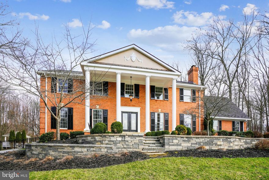 Welcome to this all-brick colonial situated high on 4.27 acres of manicured landscape, the perfect setting for its classic architecture, accentuated by statuesque 2-story columns and expansive portico.  Accent lighting highlights the extensive hardscape walls and walkways.  The 8000+ sqft of expansive living spaces showcase timeless upgrades, details and finishes.  A grand 2-story foyer features oversized molding, wainscotting, polished tile floor, curved staircase, and pocket doors for flexible access/privacy to adjoining spaces.  Elongated windows flood the formal living and dining room with natural light and picturesque views, enhanced by warm toned hardwood floors that carry through to the family room, and 15x24 gourmet kitchen.   Trending 2-toned 42"H cabinet, granite counters, 12ft island with custom bar height table and high-end appliance like 48" Subzero refrigerator and Miele built-in coffee system, this space was designed for functionality and entertainment with boundless lighting options.  The 20x30 sunroom with amazing views and direct access to the backyard amenities is a perfect backdrop for meals and family gatherings.  All 5 bedrooms are located on the second floor, including a primary bedroom with louvered shutters, ample space for a sitting area, huge walk-in closet, and a spacious bathroom with double vanity, shower and soaking tub.  The lower-level entertainment room with custom built bar is spacious enough to serve as a media, billiards and game room, elevating everything from family movie night to hosting sporting events thanks to hue programmable lighting, Sonos sound system and video matrix that perfectly synchronizes all 3 TV's at once.  Lower walk out opens to a hardscape patio and fenced wooded backyard with privacy and serenity to relax and enjoy time with family and friends.  Outdoor amenities include a saltwater pool, basketball court, gazebo and many tiered hardscape outdoor living spaces to complete your private retreat.  A bonus 30x50 detached cottage offers an additional 1200 sqft of living space,  full bath, and 1-car garage that can function as a pool house, office space, etc.