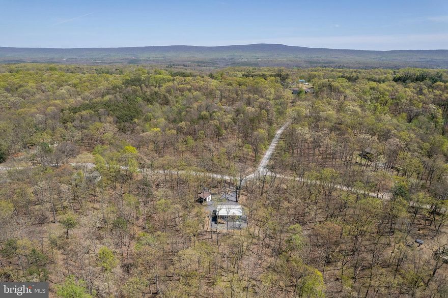 Welcome to your dream retreat! This stunning 2-bedroom, 2-bathroom ranch-style home, built in 2023, offers a perfect blend of modern comfort and rustic charm. Nestled on a generous 3.03-acre lot, this property is surrounded by lush trees and mountain views, providing a serene escape from the hustle and bustle of everyday life. Step inside to discover an inviting interior featuring an upgraded kitchen, hand-hewn wood beams, a custom made live-edge bar, locally sourced barn wood as window trim, vaulted ceilings and more. Enjoy your morning coffee or evening gatherings on the spacious deck or screened-in porch, where you can soak in the tranquil surroundings. On the outside you'll find quality building materials such as hardie-plank type siding and a metal roof. The property also includes a handy shed for additional storage, ensuring you have all the space you need for your outdoor gear. Additionally, the driveway provides ample parking for you and your guests. Embrace the opportunity to own a piece of paradise where comfort meets nature. Offering great investment potential too!