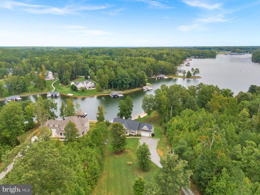 Welcome to Cucumber Cove! This stunning, one-of-a-kind, private-waterfront property is nestled in the prestigious "The Waters at Lake Anna" community. This 2016 custom-
built Craftsman-style estate sits on pristinely manicured acreage and offers over 4,200
square feet of luxurious living space, perfectly blending rustic charm with modern
sophistication. As you arrive, the natural beauty of the property immediately captivates.
The home’s inviting facade, featuring weathered wood shutters and a welcoming
covered porch, sets the tone for what awaits. Step into the soaring great room, where a
cathedral ceiling and a two-story wall of windows provide breathtaking, panoramic views
of Lake Anna. The stone hearth fireplace, ideal for cozy winter nights, anchors this
space, making it perfect for year-round enjoyment. Adjacent to the great room is the
gourmet kitchen. It’s a chef’s dream equipped with granite countertops, a large island
with seating for five, a double wall oven, and ample cabinet space. Whether you choose
to dine at the island, the expansive dining area, or out on the screened porch
overlooking the lake, each option offers its own special ambiance. For added
convenience, the fully finished walkout basement includes a second kitchen, making it
ideal for entertaining or accommodating multiple groups. This estate offers five
generously sized bedrooms across three levels, each with its own luxurious ensuite
bath, featuring a variety of walk-in closets, soaking tubs, and walk-in showers.
Outdoors, the property truly shines. The expansive wrap-around deck offers space for
relaxing and entertaining, while the hardscaped pathways lead to a private lakeside
paradise. A stamped concrete patio features a built-in firepit for evening gatherings,
while the pristine white-sand beach and nearly 200 feet of shoreline are ideal for swimming
and sunbathing. The private boathouse is a showstopper, equipped with an electric boat
lift, kitchenette, tiki bar, and a shaded seating area, perfect for afternoon cocktails or a
lakeside nap. While the natural beauty of Cucumber Cove delights – from sublime
sunrises and sunsets, deep water, and bald eagles soaring by – stay as connected as
like, with reliable in-ground high-speed fiber internet by iWisp. In addition to its exclusive
amenities, as part of The Waters at Lake Anna community, 694 Winchester Trail boasts access to a
range of recreational features, including a swimming pool, tennis courts, pickleball, a
clubhouse, and more. For investors, this property is a highly sought-after vacation
rental, offering significant income potential.  Seller strongly prefers an offer inclusive of Furniture, Boat, jet skis and other items conveying with an additional appropriate offer.  Conveniently
located just a short drive from Washington, D.C., Richmond, and Charlottesville, and
mere minutes from local restaurants, including Lake Anna Taphouse, and the Yacht Club, grocery, ABC, nail salon, a vet clinic, coffee and more!  This estate is both a tranquil escape and a gateway to year-round recreation, delivering an unparalleled waterfront experience. 694 Winchester Trail is not just a home; it’s a lifestyle. Schedule your private tour today and discover the magic of Lake Anna living!