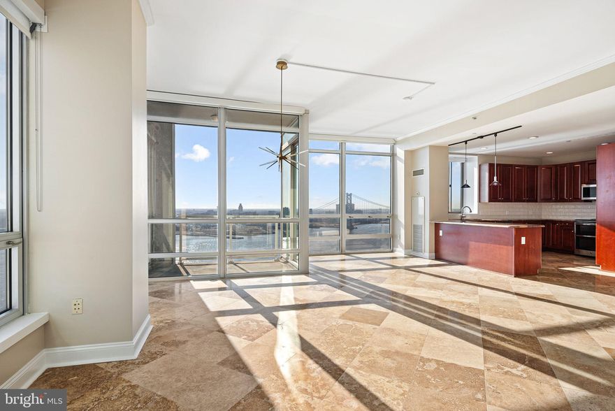 P2101 is a beautifully renovated, Northeast exposure, corner unit in the Peninsula building at Waterfront Square.  Situated directly on the river, P2101 consists of 2 bedrooms, 2 bathrooms, walk in laundry room/pantry and balcony - all with sweeping panoramic views of the Delaware River and Benjamin Franklin Bridge.  P2101 bears a completely open concept, whereas one can admire these views from the living room, kitchen or balcony - as all these living spaces are surrounded by floor-to-ceiling windows under 10 FOOT CEILINGS.  The kitchen has been enlarged from its original footprint, so the island is larger, as is the periphery of the kitchen - with additional cabinetry offering abundant storage.  The island is adorned with pendant lighting, over gleaming granite countertops that provide ample space for meal preparation.  A stylish backsplash, under-cabinet lighting, and bar seating add to the sophisticated ambiance.
This luxury condo boasts expansive large-format tiles that enhance the sense of space and sophistication. Their sleek, polished finish reflects natural light, creating an airy and elegant ambiance. Complementing the contemporary aesthetic, high-end translucent shades filter sunlight beautifully, offering privacy while maintaining a soft, luminous glow throughout the space. These premium window treatments add a touch of refinement, seamlessly blending style and functionality to create an inviting yet modern atmosphere.
Custom cabinetry with a floor-to-ceiling design is built into the living room enclave.  A sleek, rolling ladder glides effortless along a custom track, offering both convenience and a striking visual element - making a statement.
Both bathrooms feature glass showers enveloped in timeless Carrara marble. The sleek, frameless glass enclosure enhances the sense of space, allowing the marble’s elegant veining to take center stage. A rainfall shower head and premium fixtures elevate the spa-like experience.  Not to be outdone, the primary 4-piece bathroom has a stunning freestanding soaking tub - positioned to be the focal point of the bathroom.
What adds to the practicality of this unit, is that the primary en-suite is situated in the back of the home; one can simply shut the door to the primary en-suite, and it will not impede on guests' ability to access other areas of the home.  Not to mention, the walk-in closet for the primary bedroom is massive, with custom shelving.
There is a large laundry closet in the entry, housing a full-size washer and dryer, as well as a brand-new water heater.  The unit has also been freshly repainted.  One PARKING LICENSE is INCLUDED!
Waterfront Square Condominium & Spa is a premier-gated community offering 24/7 guard and gate, as well as concierge, parking, pool and hot tub with river deck, fitness center, sauna and steam room, massage rooms and community rooms.  There is a 3- level garage, with EV charging stations and Philadelphia's largest green roof situated on top.  Waterfront Square resides on a 9.5-acre riverfront enclave, with lush manicured outdoor common parks and gardens right on the river's edge.  Management is on site, and Waterfront boasts an advanced security system with closed-circuit television.  For your convenience, Global Limousine runs on site Monday-Friday, taking residents as far as 30th street and back home to their gated community.  The river deck is oversized, encompassing a 25-meter heated lap pool (junior Olympic).  Waterfront Square has an excellent location, due to its proximity to area highways & airports (676,95, all bridges), yet is nestled away on the Delaware River - the best of both worlds!  If its unequivocal luxury, showcasing the best views in Philadelphia, adorned with amenities, then it must be Waterfront Square Condominium & Spa!