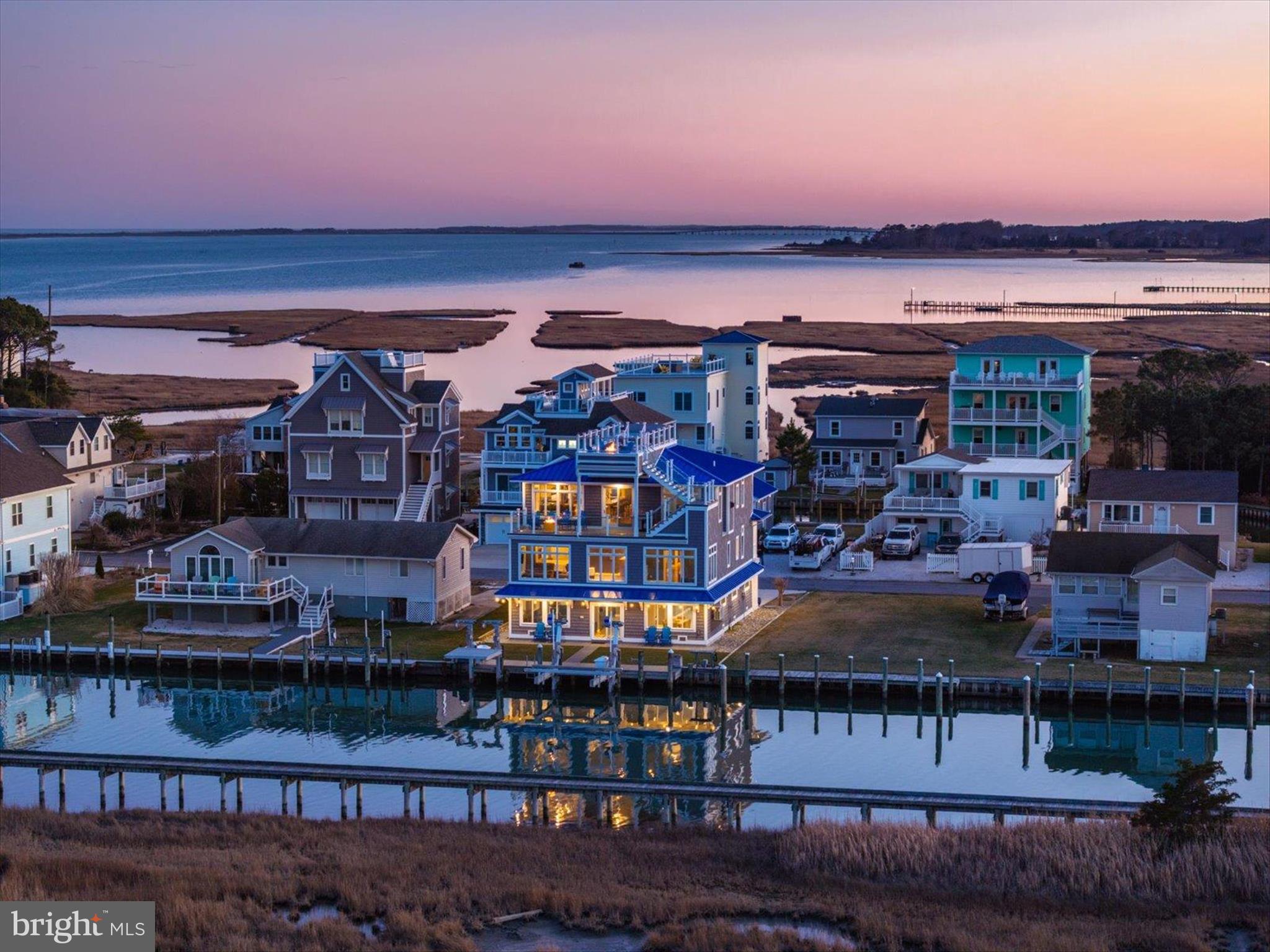 Introducing 12355 Snug Harbor Road, an extraordinary 5-bedroom, 5 bath waterfront retreat where panoramic views of Sinepuxent Bay, Assateague Island, and protected wetlands set the stage for coastal living at its finest. This architectural masterpiece boasts commanding curb appeal, crowned by a striking blue metal roof, classic shaker siding, and a gracefully turned staircase leading to beautifully appointed living spaces and luxurious outdoor amenities.
Crafted for both comfort and grand-scale entertaining, the outdoor spaces are exceptional. Multiple new Trex decks—including a rooftop oasis—offer tiered venues for al fresco living. Lounge in the built-in rooftop hot tub surrounded by a sleek glass railing system and ambient lighting, the perfect spot for soaking in breathtaking sunsets or stargazing over the bay.
The main-level deck invites casual gatherings with ample space for grilling, dining, and relaxing, all set against a breathtaking waterfront backdrop. Below, a grassy area leads to the dock, providing a serene setting for lawn games or evening cocktails by the bay. Boaters will appreciate the new 20,000 lb. IMM platform boat lift and additional swim platform lift, offering effortless access to the water for a day of cruising or fishing.
Step inside to discover gleaming Brazilian cherry hardwood flooring that flows seamlessly throughout the home, adding warmth and elegance at every turn. All windows are outfitted with remote-control blinds, allowing you to effortlessly tailor natural light and privacy while enhancing the home’s modern coastal aesthetic. New flooring and ductwork has been installed.
The entry level hosts four bedrooms including 2 primary bedrooms both with spacious sitting rooms and ensuite baths—ideal for guests or multigenerational living. A private elevator provides access to all three levels of this home. Take it to the upper level, where open-concept living is brought to life by expansive transom windows, exquisite coastal finishes and water views in all directions.
At the heart of the main level lies a spacious kitchen designed to impress both everyday cooks and seasoned entertainers. Outfitted with premium stainless-steel appliances—including a Viking gas stove, KitchenAid convection microwave, and a French door Smart InstaView refrigerator—this culinary space combines style and function. Crisp white soft-close cabinetry, trimmed in elegant crown molding, complements granite countertops, a designer tile backsplash, and illuminated display cabinets. The large breakfast bar, lit by pendant lights, is ideal for casual meals or gathering with guests. Just steps away, a sitting room and a generous dining area easily accommodate larger gatherings and opens to an outdoor balcony, offering a seamless flow for indoor-outdoor entertaining.
Throughout the main level, tray ceilings with recessed lighting enhance the sense of spaciousness and architectural detail, adding subtle drama and warmth to the open-concept design. The inviting living room offers a cozy yet refined atmosphere, featuring surround sound, a gas fireplace, wet bar, and beverage frig, and opens directly to the main deck—ideal for effortless entertaining.
A true standout of this home climate controlled fully finished garage—a showstopping “man cave” and entertaining zone in its own right. Featuring epoxy floors, a sprinkler system, commercial-grade ice maker, refrigerator, kitchenette with microwave, sink, and cabinetry, plus one Whirlpool freezer (2021), this versatile space includes a dedicated family room area, making it ideal for sports viewing, game nights, or relaxed post-boat-day gatherings.
Additional highlights include a geothermal HVAC system, closed-cell insulation for soundproofing, two Pex manifold systems, central vacuum, water softener, General Air humidifier, irrigation system, Rinnai tankless water heater, and an owned security system—all contributing to unmatched comfort, efficiency