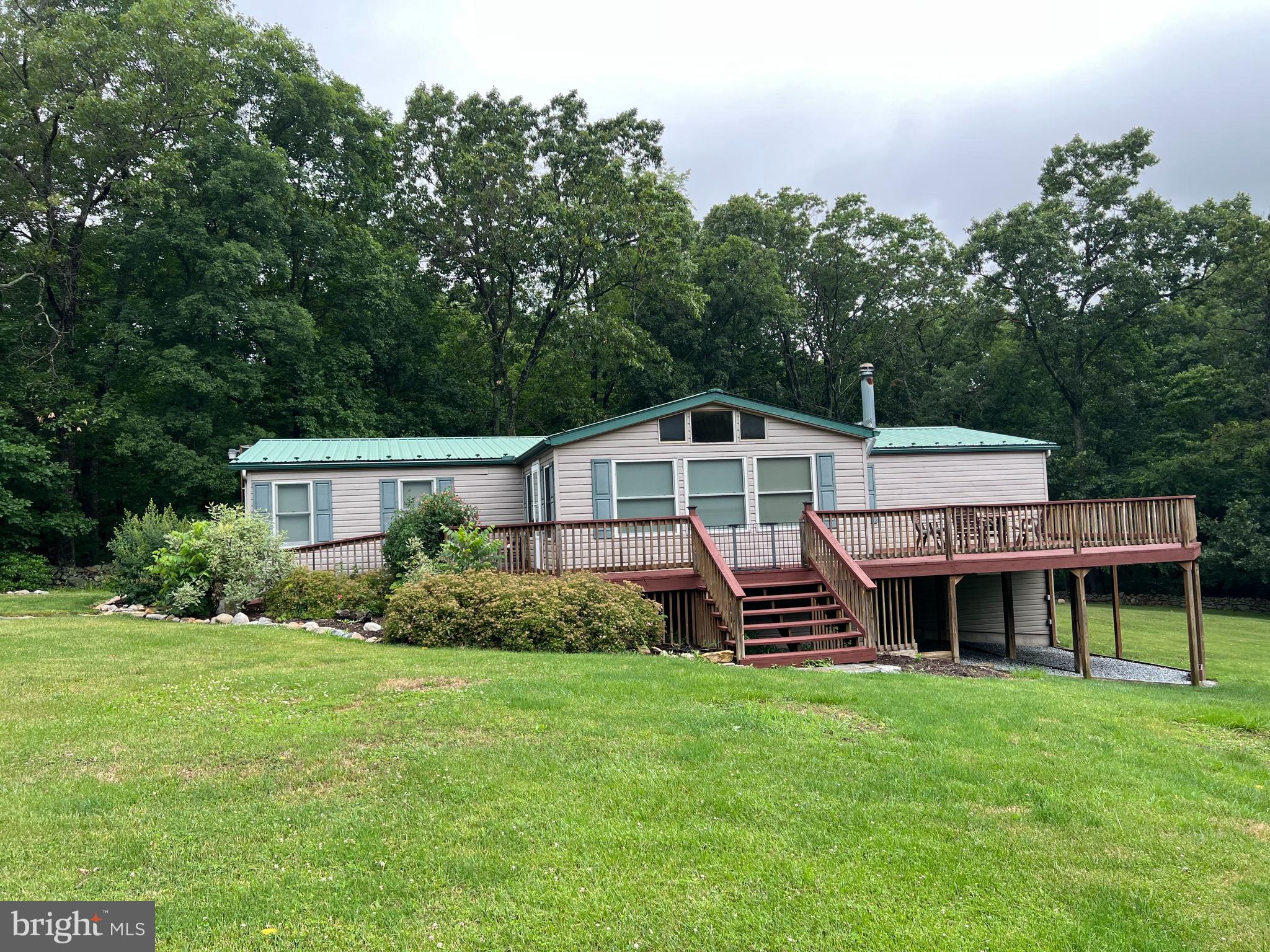 This ranch home is situated in a quiet rural community in the foothills of the Catoctin Mountains. Two of the property lines are marked by a historical stone wall. With a large open lot of over an acre, surrounded by both wooded and pastoral views, it is the perfect setting for both outdoor entertaining and peaceful respite. Enjoy family gatherings on the large, new front deck and wide open lawn, or enjoy a secluded moment with only the local wildlife for company. Ideal for the outdoor enthusiast and community oriented, this home is located just minutes from local wineries, dairy farms, state and national parks, and the Appalachian Trail. This home is in the highly desired Smithsburg High School feeder zone in the Washington County Public School District.
The ramp leading from the driveway to the front door, open floor plan, and main floor bedrooms are ideal for those seeking single-level living arrangements.
The home features a spacious open floor plan, stainless steel appliances, ceramic tile countertops thru the kitchen areas. Ceramic tile flooring in the kitchen and laundry areas. Pergo flooring in the main living areas, a metal roof, and a bright sunroom with stamped concrete flooring. There is a hearth and chimney in the sunroom ready for a woodstove for cozy winter days. Cathedral ceilings throughout the home, plus newly replacement windows and a recently updated HVAC system less then 5yrs old contribute to comfortable living. Shed has electric to it. Driveway is share with 1 neighbor there a right-a way in the deed. Don't let this opportunity slip away. Listing agent is a Md. licensed realtor.