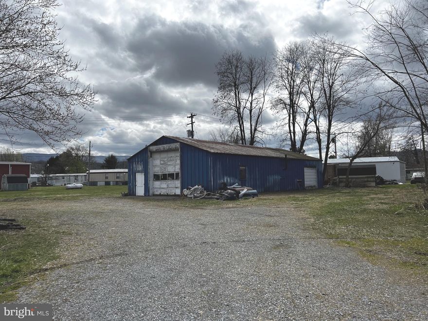 Great location in middle of town adjacent to South Branch of Potomac  River, Protected by Corps of Engineers dike. Both the metal and block buildings have been used as auto body shops for past 50+ years. Public water and sewer are available, as well as three phase electric.  Perfect for a granite/marble business with the tall garage doors and concrete floors! Level the buildings and place your own shop or business here!