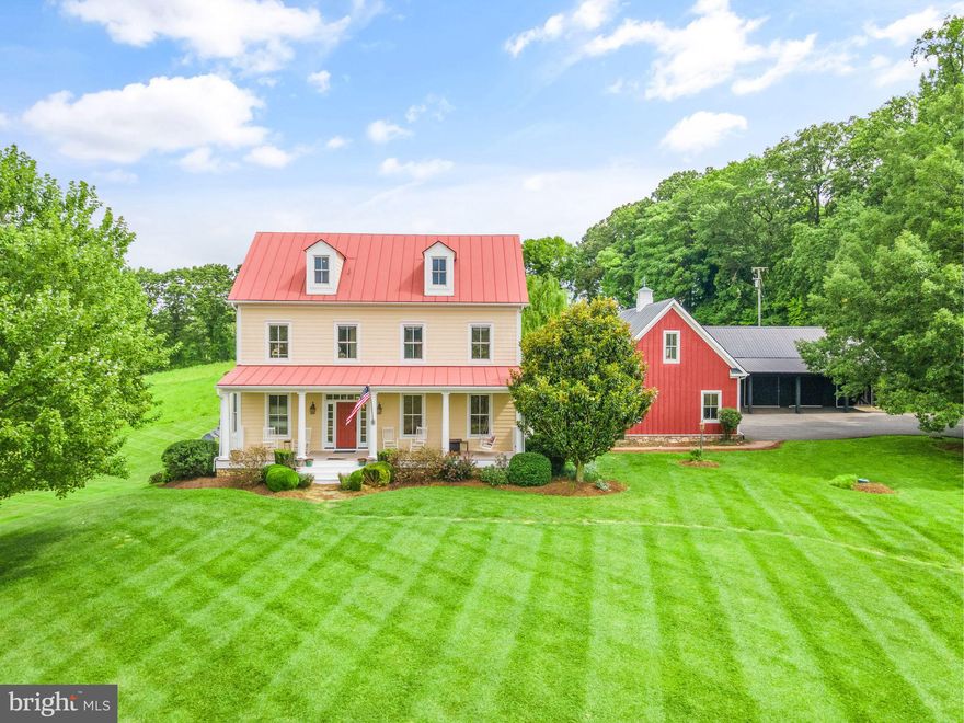 Nestled within the charming and historic area of Paeonian Springs near the quaint village of Waterford, this custom-designed farmhouse built in 2003 pays homage to the architectural aesthetics of the 1700s. Set on nearly 12 acres of picturesque landscape, this residence seamlessly combines modern amenities with period-appropriate design, creating a harmonious blend of past and present. The farmhouse spans four levels, each meticulously crafted to capture the essence of colonial architecture. The exterior boasts a classic design with a wide, welcoming front porch. The interior showcases the craftsmanship of a bygone era while offering the comforts of contemporary living. The design carefully incorporates elements such as transom windows, hand-hewn cherry and oak flooring and period-specific fixtures, transporting occupants to a time when craftsmanship was an art form. With four bedrooms and five bathrooms distributed across various levels, the farmhouse ensures ample space for both family and guests. Relax in the primary suite next to the wood-burning fireplace or take in the views from your private balcony. The unfinished attic is easily accessible and just waiting for your creativity. Rough-in plumbing is already in place along with an electric panel, HVAC ducts and vents and several windows. The lower level features a spacious and fully finished walk-out basement, complete with a media room, exercise room, storage room, and an open pub-style entertainment area, complete with mahogany bar tops, built in cabinetry, dishwasher, sink, beverage refrigerators and a wood burning fireplace. Head outdoors onto the paver patio with beautiful stone retaining walls and be surrounded by nature. For car enthusiasts and hobbyists, this property offers a three-car attached garage and a separate four-car detached garage. Ascend to the level above the main garage, and you'll find a hidden gem with it’s own entry—an expansive attic space brimming with potential. Finish it to your liking, and it could become a grand office, a playroom, or a studio. The latter offers space for car collections, a workshop, or even the potential for a guesthouse conversion. The Pennsylvania Amish pole barn is 24’ x 40’, complete with 4 doors and side entry access and was constructed with scissor trusses in order to accommodate a future second floor. The metal roof and board and batten siding complement the main farmhouse. Enjoy the glorious sunrises and sunsets while still being close to shopping, restaurants, schools, Dulles Airport and the Metro for events in Washington D.C. Experience the annual Waterford Fair, holiday parades, weekly farmers market or take in music from local artists at one of the many wineries and breweries, just minutes away. This custom-designed farmhouse offers a rare opportunity to live in a piece of history while enjoying the comforts of modern living. From the wrap-around porch to the spacious attics, this home is a testament to the enduring allure of 18th-century architecture and the dream of rural living. With its period-correct design and luxurious amenities, it truly represents the best of both worlds—a timeless masterpiece in the countryside yet close to modern conveniences.