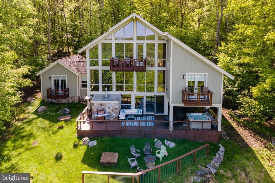 Perched atop a scenic mountain overlooking Deep Creek Lake, this stunning 5-bedroom, 5.5-bathroom home offers breathtaking views and ultimate privacy. Spread across multiple levels, the open-concept design features a grand living area with soaring ceilings, a stone fireplace, and large windows to take in the surrounding beauty. The gourmet kitchen, with top-tier appliances and a spacious layout, flows into both a formal dining area and an opening living space. The primary suite boasts a private deck, walk-in closet, and a luxurious spa-like bath. Each bedroom has its own en-suite for added comfort. Outside, a large deck with a hot tub and lake views invites relaxation. With lake access and your very own dock slip for boating, plus proximity to WISP  resort for skiing and winter fun, this home offers year-round recreation. Additional community features include: a private gated entrance, a seasonal outdoor pool, tennis courts, basketball courts, and a full lakeside area with ample parking, bathrooms, dock slips, & more. Whether for a family retreat or primary residence, this mountaintop gem offers the perfect blend of luxury, adventure, and serenity!