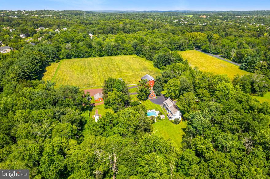 Gorgeous Bucks County Farmstead gracefully nestled on a scenic, tranquil backdrop of rolling country land that offers the utmost in privacy yet is convenient to everything. Over 20 acres of beautiful meadows, hayfields, open space, endless perennial gardens, rustic spring house with neighboring creek and more! This truly inspiring and lovingly preserved hobby farm offers a perfectly positioned main house, carriage house, large barn with stalls and gallery space, detached 3-car garage, pole barn and greenhouse.  The stately tree-lined drive is a precursor to the beauty that awaits. The antiquity and sustainable space in the stone farmhouse offer a glimpse into its 1700’s past while bestowing some modern touches although maintaining the historic charm. Features include 4 bedrooms, 3.5 baths, bonus third floor flex space which can be utilized as a studio or fitness space and partially finished lower-level ideal for a billiard/pub room. Abundant in character, this vintage beauty showcases skillfully crafted exterior and interior stonework along with deep windowsills, exposed beam ceilings, period hardware, cedar roof, 5 wood-burning fireplaces, wood floors and built-ins throughout. Relax outdoors on the covered back porch or lounge at the saltwater pool with convenient pool house highlighting a full bath while admiring the wildflowers and long distant meadow views with the sounds of nature all around. Guests can enjoy their own serenity in the eye-catching, spacious Carriage House featuring 3 bedrooms, 2 full baths, kitchen and living space adorned with wood beam accents and a sizeable picture window to admire the grounds. The lower portion of the classic Red Barn can easily host horses and other animals with multiple stalls while the upper portions are finished to accommodate a multitude of uses. In the past, this included an art studio and gallery, but any collector will delight in this space as well as the separate Pole Barn building.   So much to be discovered on this glorious compound bordering 50 acres of preserved land. Meander through your own nature preserve and hike on your own walking trails, grow your own vegetables, and raise farm animals while enjoying this hidden piece of paradise showcasing charm and cozy living quarters. The mural-like setting located just minutes from downtown Doylestown, exemplifies one of the finest properties in Bucks County with its traditional design and every amenity appreciated for today's lifestyle. *****The land has yet to be preserved. Opportunity for a Conservation Easement and Separately deeded 2 acre building lot can add even more value to this special property. Enjoy low property taxes under Act 319.