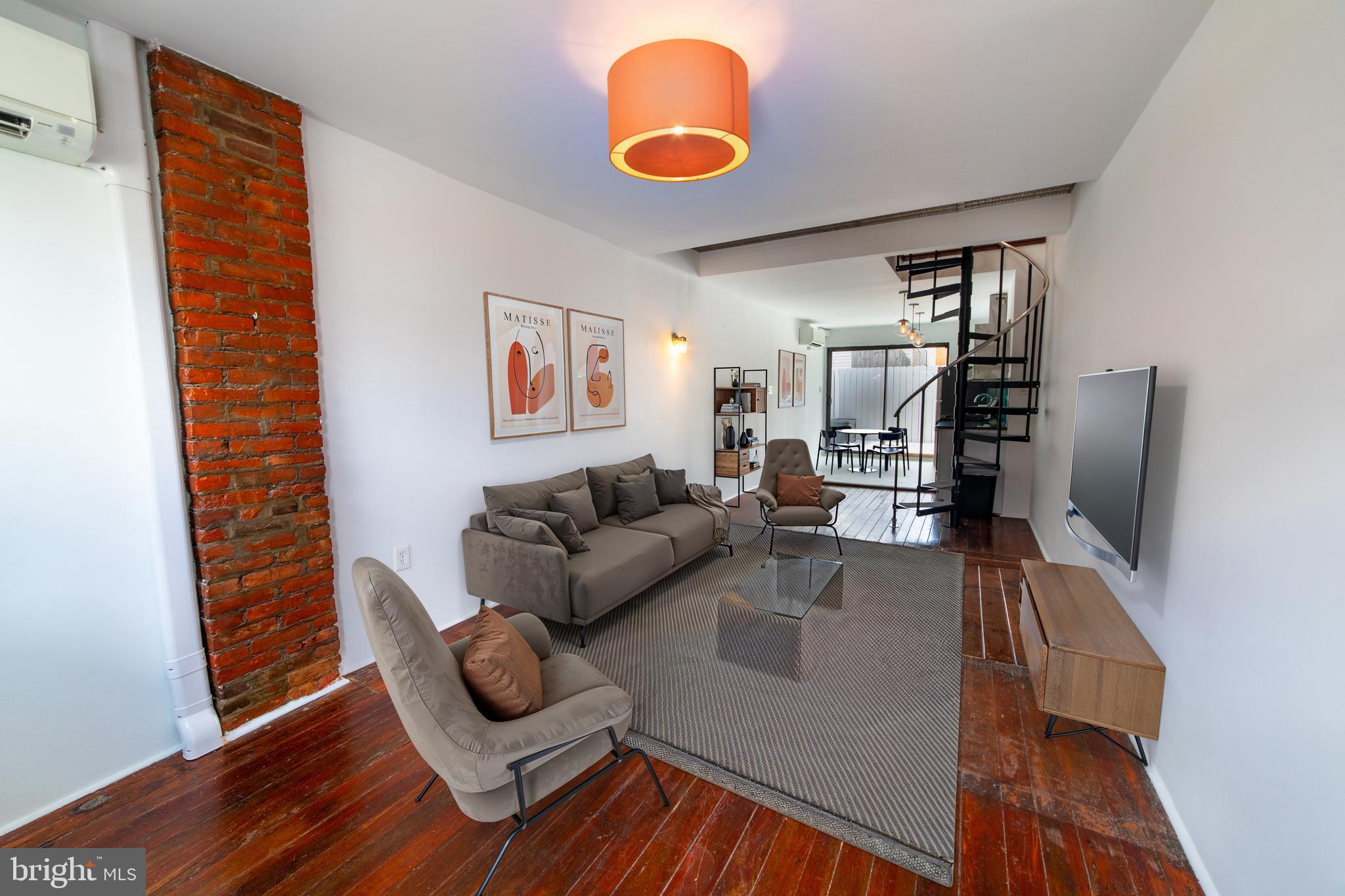 Welcome to this one-of-a-kind, fully renovated two-story rowhouse offering the perfect blend of modern style and classic Philly character. This thoughtfully updated home features an open-concept layout with original hardwood floors, exposed brick walls, and a striking spiral staircase. The turquoise backsplash brings a lively splash of color and character to the kitchen, beautifully accenting the sleek appliances and custom design elements throughout. A unique architectural feature—a ceiling opening with a removable grate connects the upstairs and main living area with added light, airflow, and makes moving furniture between floors a breeze. Upstairs, enjoy a bright and airy bedroom with flexible layout options and a reclaimed wood sliding barn door leading to a spa-like bathroom, complete with a dual vanity and walk-in tiled shower. Step outside to your private, fenced rear deck—ideal for entertaining or relaxing. The unfinished basement offers a washer and dryer and ample storage. The new ductless HVAC system with 2 units on the first floor and 1 on the second floor was installed in March of 2025, and the new roof is only 4 years old. This home has been well maintained, the interior was just painted, and the deck and fence were stained. This home is move-in ready! Located just steps from Frankford Avenue and Girard Avenue’s vibrant shops, dining, and nightlife, with easy access to public transit, I-95, and neighborhood parks. Only a 15 min walk to Market-Frankford Line and 20 min drive to the airport. Down the street is a fenced and well-maintained dog park, basketball courts, and a playground. Urban living never felt so comfortable—or so stylish!