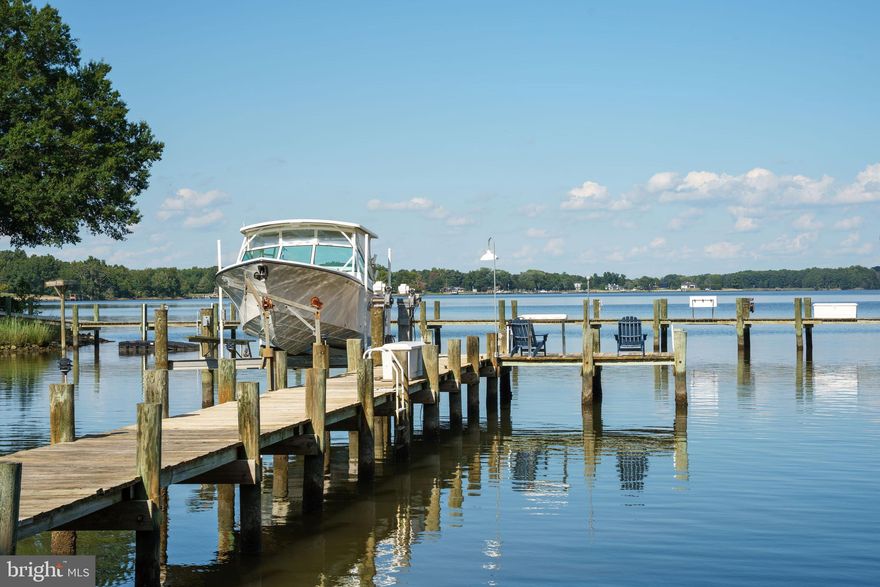 Set on more than five tranquil acres with deep water and over 900 feet plus of protected shoreline, this custom-built waterfront residence new finished square footage 7,129 feet offers timeless design, enduring quality, and a setting unlike any other. With five full en-suites and newly finished spaces for a second family room & kitchenette, it provides flexibility for multi-generational living or exceptional guest accommodation.
Originally built in 1981 and completely reimagined in 2006, every detail reflects craftsmanship and artistry. A gated entry and private drive lined with seasonal blooms lead to a circular drive and covered brick porch, where glass entry doors open to reveal soaring vaulted ceilings, skylights, and a wall of windows framing the breathtaking Wye River views.
Throughout the home, custom cherry millwork elevates fireplaces, built-ins, and displays with warmth and richness. At the heart of the open floor plan, the gourmet kitchen is outfitted with Alder cabinetry, Sub-Zero refrigeration, three wall ovens, a five-burner cooktop with grill, and a warming oven—designed for both entertaining and everyday living. Formal dining beneath a vaulted ceiling, casual meals at the breakfast bar, or dining al-frescos on the composite deck all capture sweeping water views.
Outdoors, cascading deck stairs open to a lush lawn and private pier with boat lift in deep water, offering endless opportunities for boating, kayaking, and sunrise views.
Inside, thoughtfully designed spaces accommodate every lifestyle need. A professional office with private entry is ideal for working from home, while a separate en-suite suite with private stair access provides perfect quarters for guests or an au pair. The main-level primary suite features soaring ceilings, panoramic river views, and a spa-inspired bath with onyx floors, jetted tub, walk-in shower, and dual vanities. Upstairs, two additional en-suites and a cedar closet complete the private wing.
The walk-out lower level expands the living experience with a recreation room, gas fireplace, full daylight windows, a full bath, and covered patio access. Flex rooms, abundant storage, and a generously sized workshop/studio make the home as practical as it is luxurious. In addition, there is 776 sq. in basement that could be finished if necessary or used as storage.