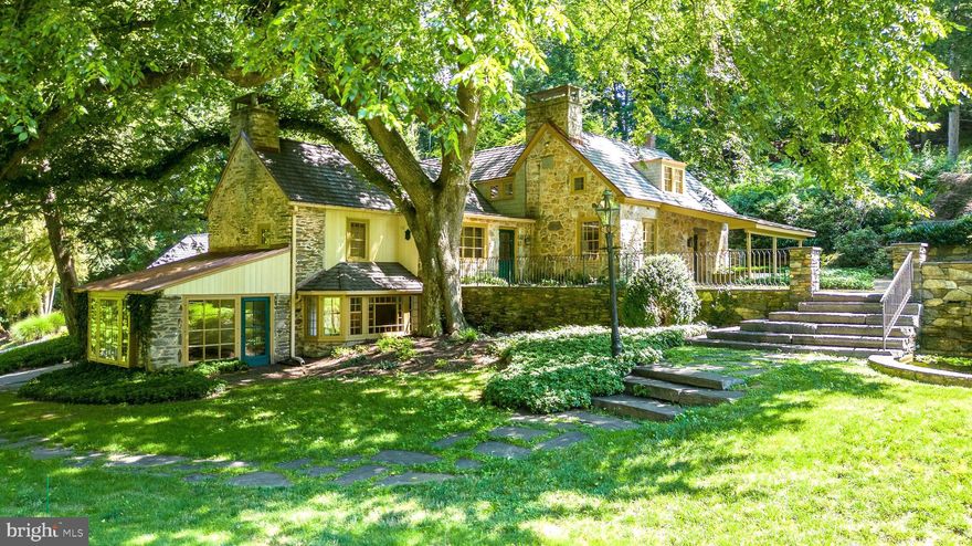 Tucked into over 12 acres of permanently conserved land and enveloped by lush landscaping, directly across from a 90-acre park, this stunning 5900-square-foot stone farmhouse offers a private sanctuary surrounded by captivating natural beauty known as Snug Valley. With its charming three-story design, this home boasts an aura of elegance and tranquility. A gated drive accesses a long private driveway. As you approach, you'll be greeted by a meticulously landscaped property, preserved by the Natural Lands Trust, adorned with specimen trees and shrubs, creating a truly picturesque setting. The gorgeous grounds feature multiple ponds, adding a touch of serenity to the already idyllic atmosphere. Stepping inside, you'll be captivated by the character of this residence. The house showcases a remarkable blend of historic charm and modern comforts. The high ceilings and exposed beams throughout the home create a sense of spaciousness and character, while the natural light cascading through the windows with deep windowsills accentuates the architectural details. Each room is thoughtfully designed to offer both comfort and style, with ample space for relaxation or entertaining. The new roof and siding ensure that this home is not only beautiful but also well-maintained. The first/entry floor features a sun-drenched Sunroom overlooking the grounds and connects to the spacious Family Room with walls of custom bookshelves and exposed beams. The main floor offers a fabulous Living Room adjacent to the classic Kitchen with honed granite counters and stainless appliances offers a charming pantry/eating area with new wine fridge and new counter. The connecting Dining Room with walls of windows can accommodate a large number of guests. The Primary Bedroom suite on this floor features a full wall of closets, a Spa/Dressing Room with vaulted ceiling and 2 separate bathrooms. A 2nd Bedroom on this floor includes a separate Full Bath. The 3rd floor features 3 additional bedrooms, a renovated Full Bath with marble counter, plus an Office, and the back staircase accessing this area offers the opportunity for an in-law/au-pair Suite. A finished area above the Garage would be an ideal Gym, Game Room or Art Studio and includes an extra storage room. 2 Ponds and 3 interconnected Water gardens are further complimented by brick patios, extending the living space outdoors, inviting you to enjoy the beautiful surroundings and entertain guests amidst nature's splendor. Whether it's a quiet morning coffee or an evening soiree, these patios provide the perfect ambiance for every occasion. Other structures include a charming stone storage barn, a newer covered shed, a spring house and a pump house. Other special features include a whole house generator, landscaping irrigation system and security system. A portion of the property is located in Tredyffrin Township, however all taxes are paid to Upper Merion. Speaking of taxes, they are incredibly low due the protection of Act 319 (the Clean and Green Act). Conveniently located near King of Prussia and the town of Wayne, and providing easy access to center city, this property offers a harmonious blend of seclusion and accessibility. You can relish the peaceful retreat this house provides while still enjoying the nearby amenities and attractions. Find a touch of the Cotswolds in Upper Merion.