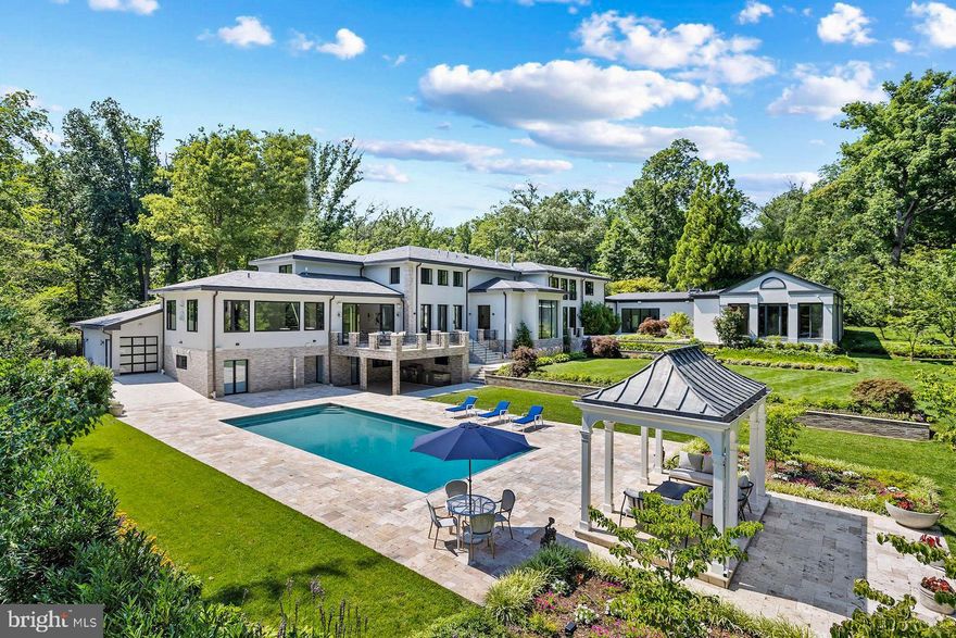 Prominently positioned yet discreetly tucked away on a quiet, winding section of famed Fernwood Road in legendary Bradley Hills Grove, this is one of those truly special homes where not a single detail has been overlooked. Painstakingly reinvented with obsessive attention to detail and the finest international materials, all 15,000 square feet of living space has undergone a complete transformation â the result of which is an estate with an old soul clad in contemporary finishes. The driveway, with its intricately inlaid criss-crosses of grass, evokes a distinctly Californian charm conveying a sense of airiness carried throughout the home. Light floods the 19 foot greeting hall and gives way to a stunning open-slab glass staircase whose transparency allows light from the double-height wall of windows beyond to permeate inwards. Fine workmanship and top-notch materials are evident everywhere, an example of which can be seen with custom built imported interior doors. Elegantly proportioned formal spaces live up to the substantial square footage, enabling entertaining on the grandest of scales. Yet, the thoughtfully designed floor plan is equally apt at accommodating everyday living. As the heart of the informal space, the chefâs kitchen boasts an oversized quartz-topped center island and two large windows letting in abundant natural light. Sleek European style cabinetry conceals a full suite of top-of-the-line Miele appliances, including a 48-inch commercial range and twin wall ovens. A large primary suite completes the main level, facilitating multigenerational living. Reaching the upper level via stairs or one of two elevators, the second primary suite, with its raised ceiling, has three sets of French doors which reveal sweeping views of the rear garden and pool. Its spa-inspired bath features twin floating vanities, a freestanding tub, a walk-in shower concealed by custom smoked-glass doors, and, along with every other bathroom in the home, radiant heated floors. The custom dressing room is equally minimalist with dark mirrored doors concealing all shelving and a large center island. Amenity-rich, the estate boasts a fully-equipped covered outdoor kitchen with Wolf appliances, as well as an extensive stone terrace. The terrace steps down to an immaculate patio housing the newly resurfaced outdoor pool with automatic retracting cover and a charming gazebo beyond. The indoor swimming pavilion, gym, hammam, and steam room affords year-round usability. Back outside, manicured lawns extend into the treeline, which creates a canopy of privacy along all 2.77 acres of space â a hardly believable acreage for close-in Bethesda. Built like a fortress from concrete and steel, commercial grade systems work behind the scenes to run the estate, not limited to twin generators, a new roof, new sprinkler system, new contemporary garage doors, no less than eight HVAC units, and a comprehensive audio/visual system encompassing surround sound as well as security video surveillance. Unparalleled in design and execution, 8801 Fernwood Road is premium in every square inch. Combined with its rare large lot in an incomparable location blending privacy and accessibility, this is a home for the most discerning buyer and undoubtedly one of Bethesdaâs great estates.