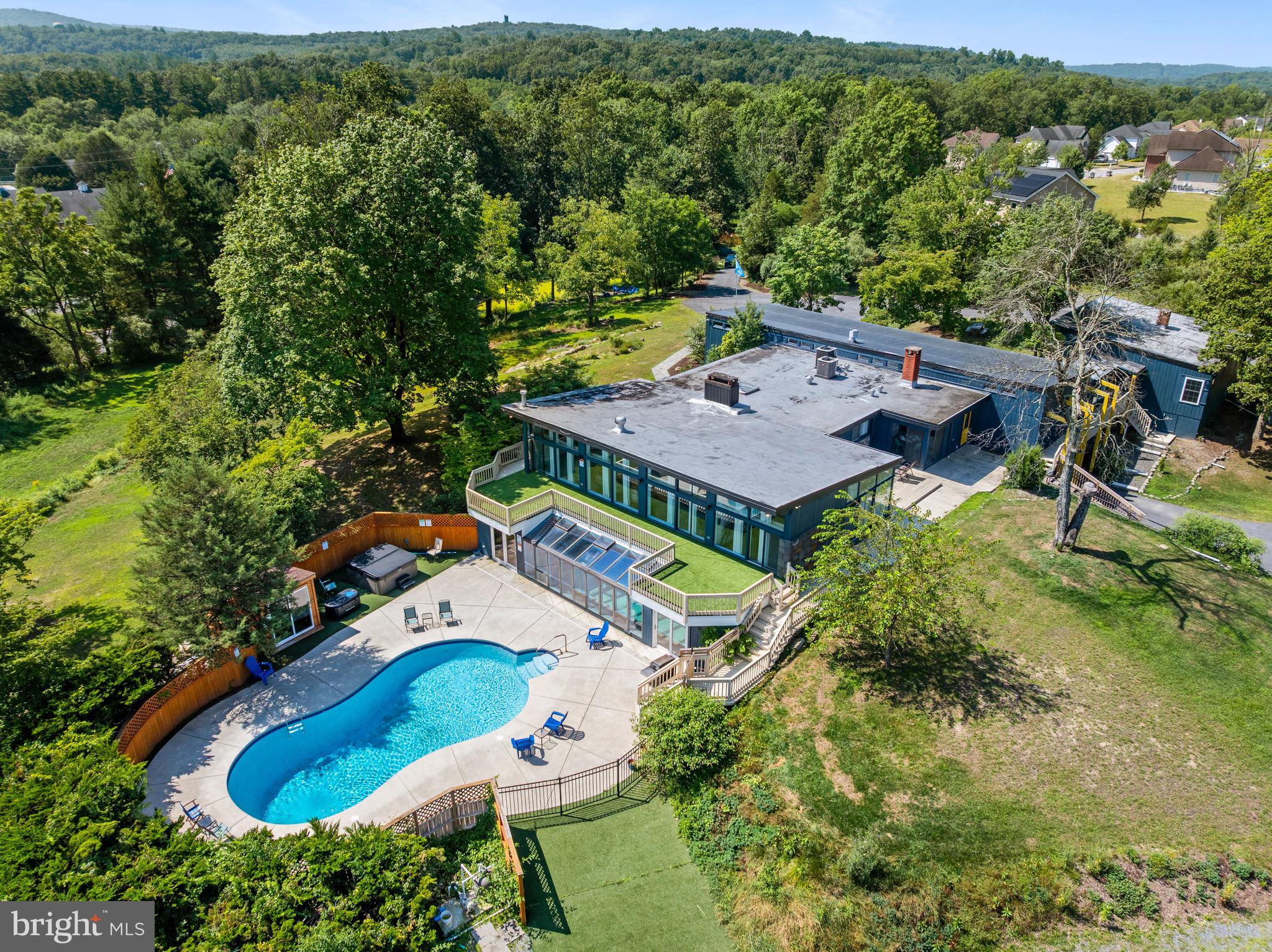 Welcome to paradise!
Discover a premier Poconos destination with this extraordinary home, boasting nearly 10,000 square feet of luxurious living space on a sprawling 3.7-acre lot. This magnificent property features its own private pond and ample space to create your dream landscape while enjoying the privacy that it has to offer.
This home is an architectural masterpiece with lofty ceilings, expansive walls of windows showcasing the views, and a chic mid-century modern design enhanced with unique touches by the current owners. As an active vacation rental, it generates significant income and holds immense potential for the right operator. Or, make this spectacular home your own private retreat.
Need a pool? How about two of them!—an outdoor pool for seasonal enjoyment and an indoor pool for year-round relaxation. Additionally, the home includes a sauna, hot tub, and cold plunge for the ultimate spa experience.
Upon entering the spacious foyer, you'll be greeted by a lush wall of jungle-themed greenery, a design element that flows throughout the home. The main living area features floor-to-ceiling windows overlooking the outdoor deck and pool area, a cozy fireplace, ample seating, and a unique epoxy table. The main floor also includes two game rooms and a charming breakfast area, which is next to the contemporary kitchen which is fully equipped to meet all your culinary needs.
The main level hosts five uniquely themed bedrooms, each with its own in-room seating area and rich design themes including the "Tiger Room" and "Peacock Room,"the reasons for these names being evident as you tour the home. Three of these bedrooms also feature private balconies. A separate guest suite, accessible via a delightful walkway, offers a more traditional design with its own full kitchen, lofted living space, two spacious bedrooms, and a full bath, functioning as a complete home within the home.
The lower level adds to the home's appeal with a large custom bunkroom, laundry facilities with three sets of washers and dryers, a second spacious living area with a fireplace, a full bath adjacent to the indoor pool area, and a unique mystery room. Utility rooms, abundant storage, and garage space complete this level.
Situated just 1.5 hours from NYC and a short drive from many premier Poconos destinations including Kalahari Waterpark, Camelback & Shawnee Ski areas, Bushkill Falls, and many more, this home offers endless entertainment options. Shopping, dining, and golf are also within minutes. With so much to do, you might never want to leave this paradise!
Don't miss the chance to own this piece of Poconos paradise—come takethe tour and experience it for yourself!