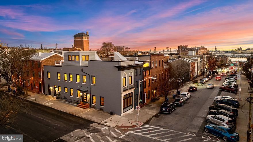 Happy holidays from 401 S. Chester Street! This expansive, one-of-a-kind residence sits just off the Baltimore waterfront at the crossroads of three iconic neighborhoods, offering an exceptional blend of character, scale, and city amenities—all in a single address. With approximately 3,100 sq. ft., the home was expertly renovated and expanded only a few years ago, featuring stylish, high-end finishes throughout while preserving its historic charm. Inside, you’ll find 3 bedrooms, 3.5 bathrooms, and a host of unique features, including a potential in-law suite or rentable lower-level apartment with private access, plus a generous exterior storage area perfect for bikes and outdoor gear.

Even before stepping inside, the exterior sets the stage with grand scale, original marble details, and a distinctive storefront-style window that hints at the thoughtful design within. From the front door, Baltimore’s waterfront glimmers at the end of the street, while Patterson Park—Baltimore’s own “Central Park”—offers sweeping green space, free summer concerts, community events, playgrounds, sports fields, and dog parks. Holy Rosary Church stands just across the street, Johns Hopkins Hospital anchors the backdrop, and the vibrant energy of Canton, the historic charm of Fells Point, and the luxury of Harbor East are all within easy walking distance.

Inside, the home immediately sets its tone—warm, dramatic, and unmistakably Baltimore. Wide-plank floors, exposed brick, and soaring raftered ceilings wrap the main level in character, while industrial details blend seamlessly with modern finishes and historic craftsmanship, creating a space that feels cohesive, inviting, and rich with personality.

To the right of the foyer, the living area opens with a generous sense of volume. Lofted ceilings, exposed beams, and an original brick wall are anchored by a signature storefront-style window that fills the room with natural light. The result is both cozy and expansive, a natural gathering place where texture, height, and light come together beautifully.

To the left of the foyer, the eat-in kitchen impresses with a spacious center island, quartz countertops, a custom marble backsplash, and stainless steel appliances. There is ample room for a full dining setup, while a stylish powder room and coat closet add convenience to the main level.

The second floor offers two generously sized owner suites, each with walk-in closets, abundant natural light, and beautifully remodeled en suite bathrooms. A dedicated laundry room on this level makes everyday living effortless.

One level up, discover a sun-drenched bonus room wrapped in windows and complete with an industrial-style wet bar. This lofted sunroom opens directly onto a private rooftop deck—recently replaced and covered by a transferable roof warranty—perfect for entertaining, enjoying fireworks or air shows, or relaxing with morning coffee.

The fully finished basement adds even more versatility, featuring high ceilings, its own entrance, a living area with wet bar or kitchenette, a full bathroom, and bedroom—ideal for guests, a home office, gym, au pair suite, or income-producing rental.

Outside, an additional exterior storage room provides ample space for bikes and gear, and one year of prepaid parking in the nearby church lot is included. Ideally located for Johns Hopkins employees or city lovers alike, 401 S. Chester Street offers walkable access to waterfront paths, shops, restaurants, the water taxi, and everything Patterson Park has to offer, making this one of the most architecturally unique and livable homes in the area.