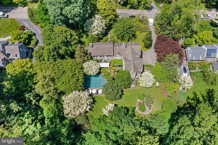 Presenting a pristine, masterfully updated 1937 Okie-style Colonial Revival, originally inspired by the historic Appleford mansion in Villanova. Designed by renowned Philadelphia architect E. Nelson Edwards, this home was envisioned in the spirit of a classic Pennsylvania farmhouse—a style beloved and elevated by Brognard Okie. With its exceptional architectural pedigree and historic charm, this is truly one of the Main Line’s legacy properties.
Every detail of this home was crafted with intention: arched doorways, softly rounded transitions, barn doors, random-width hardwood floors, dentil molding, and inset chair rails all speak to its original artistry. Authentic Baldwin Brass hardware and pewter sconces—faithful reproductions of 19th-century originals—further preserve its historical character.
The current owner, a seasoned interior designer,  has seamlessly blended modern functionality with timeless style throughout. Upstairs, you’ll find four bedrooms, including a luxurious Primary Suite with a private dressing room, soaking tub, and steam shower. The second bedroom boasts a private en suite bath, while the third and fourth bedrooms are connected by an elegantly appointed Jack and Jill bathroom, combining style and convenience with timeless charm.
The first floor is both elegant and practical, featuring two half baths, a laundry room, mudroom, and spacious walk-in pantry. The designer chef’s kitchen is a showpiece—outfitted for entertaining with Viking ovens, a warming drawer, Bosch dishwasher, 48” refrigerator, and soapstone countertops. A custom walnut island and bar peninsula complete the space, which opens to a sunlit family room featuring one of the home’s four gas fireplaces and panoramic views of the gardens.
The finished lower level expands the living space with a game room, wine storage, gym, sauna, utility room, and a charming gift-wrapping station. A separate lower-level suite—with its own kitchenette, full bath, and ample storage—offers a private haven for in-laws, guests, or a live-in nanny.  An attached two car garage featuring automatic doors, a utility sink and access to the central vacuum system rounds out the lower level.
Step outside into what feels like a French countryside retreat. Set on a lush, park-like lot, the home is surrounded by curated gardens, flowering shrubs, and mature trees that provide year-round beauty and privacy. The backyard borders an 8-acre protected forest, ensuring rare seclusion in the heart of the Main Line.
Anchoring the landscape is a custom gunite pool with an automatic cover, framed by a stone terrace and blooming garden beds—perfect for summer gatherings or tranquil mornings. Multiple seating areas are nestled into the landscape, ideal for sunbathing, reading, or hosting alfresco dinners beneath the stars.
A charming gazebo sits at the edge of the woods, a serene spot for afternoon tea or quiet reflection. The outdoor kitchen—complete with a wood-burning fireplace, built-in pizza oven, Coyote grill, and integrated BBQ station—sets the stage for grand-scale entertaining. Nearby, a cedar hot tub offers a peaceful retreat under a shaded canopy of trees. A luxurious outdoor shower, featuring both rain head and hand-held options, completes the spa-like ambiance.
Thoughtfully positioned to maximize light and landscape, the entire home overlooks the exquisite, custom-designed pool and beautifully manicured grounds.
This is more than a beautifully maintained home—it’s a generational estate, meticulously preserved and thoughtfully updated, with architectural roots embedded in the rich fabric of the Main Line. Located in the coveted Lower Merion School District with easy access to major roadways, it’s the ideal blend of heritage, comfort, and convenience.
Come tour this extraordinary property—and experience a piece of living history.