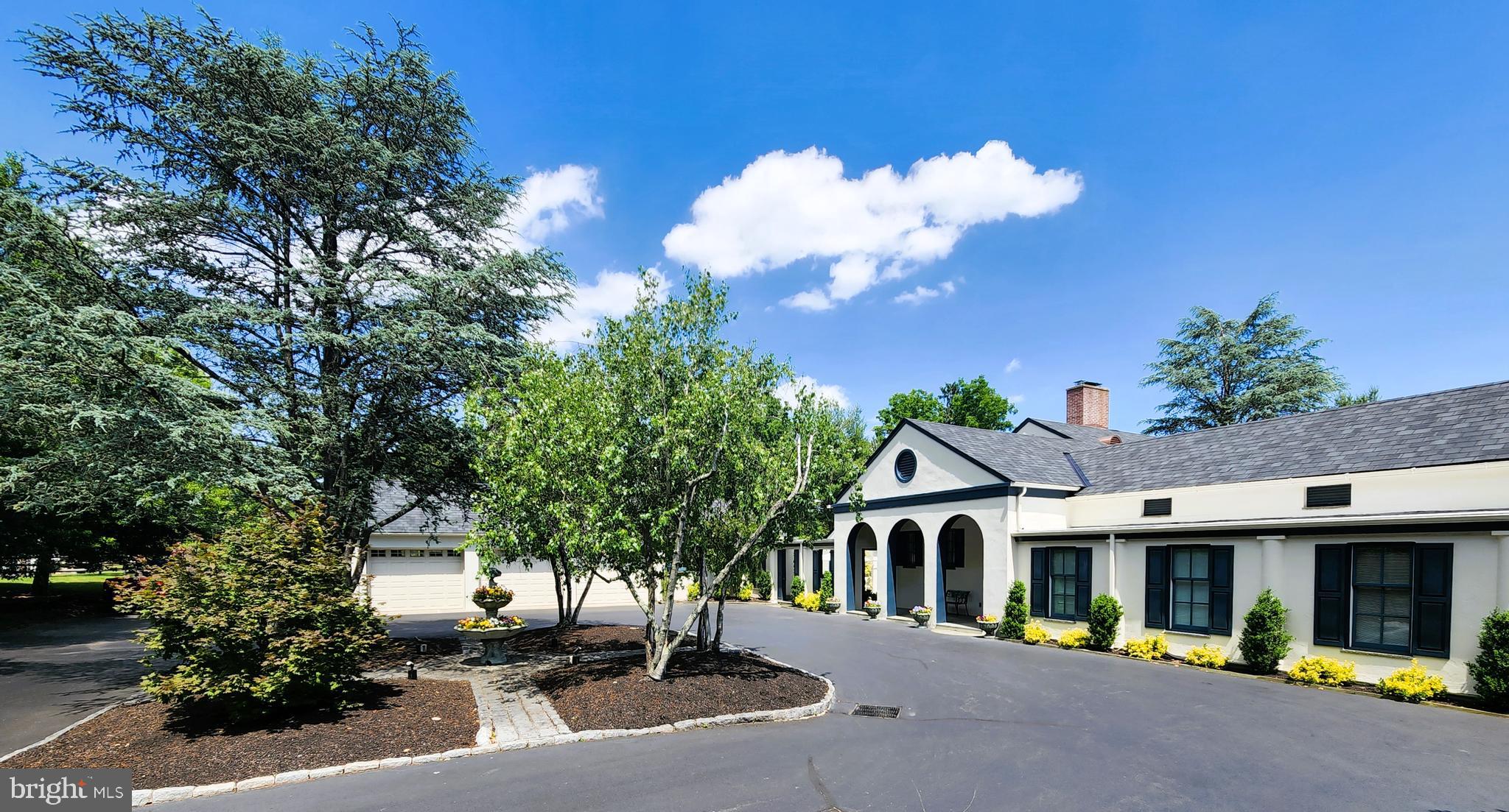 This beautiful Villa in Blue Bell presents luxurious suburban living both indoor and out! The bucolic tree lined property sits on over three and a half cleared acres and delivers just over six thousand square feet of living space. On first approach as you enter the courtyard you will notice the brand new Belmont CertainTeed shingle roof w/copper trim and custom copper brow attic vents, the covered front porch, and a three car garage (w/ bonus room and half bath). Enter the property and find a marble foyer w/ a large walk-in closet and adjacent powder room. From the foyer, enter the formal living room or exit right or left to either wing of the home. The formal living room has near twelve foot ceilings and an exotic wood finish, a large gas fireplace and magnificent huge cherry windows and patio doors that provide sweeping views of the property. To the left is a spectacular formal dining room w/ teak wood walls, floor-to-ceiling built-in custom cabinets, and a beautiful large brass chandelier. Back to the foyer, a quick right down a short hall brings you to the East Wing. First, a spacious family room, w/ a large gas fireplace set in stone from floor-to-ceiling opposite an entire wall of built-in bookcases and cabinets. From this room you can access the gazebo and in-ground pool via an oversized Kolbe door, or go down the halls that lead to 3 of the 6 bedrooms. The shorter hall leads to the MB which has 4 windows and 4 closets: 2 large corner built-in closets w/drawers, and shelves, a 6’ double door, double rod closet; and a walk-in closet. The MB ensuite has a double hung window, a 7‘ granite counter top w/ a single sink, a 3 drawer center cabinet, a sit down vanity w/large center drawer, linen closet, walk-in shower w/granite bench and separate handheld and overhead faucets. The longer hall, 45’ carpeted, w/ its own exterior private entrance has 2 great sized bedrooms w/ ample closet space and their own recently updated ensuites. Back to the foyer, turn left and start the tour of the West Wing down a short marble hall where the laundry closet and storage reside. Directly across from the laundry area is a giant built-in storage wall of large deep drawers, and shelving to the ceiling. A few short steps you may either go outside to the covered walk, driveway, garage and bonus room, or to the eat-in kitchen with 2 spacious closets, kitchen table, white painted cabinets w/ black button brass pulls, 2 long countertops on opposite sides, one has a large 33” SS sink and the other a 25” Franke sink, 2 dishwashers, and 2 refrigerators: a 44” SUB ZERO French door refrigerator and an under-the-counter SUB ZERO refrigerator, GE Profile gas stove, w/ an over-range microwave, a Jenn-Air drop-in counter e/grill, and a 44” island workspace w/contrasting white quartz countertop, a cherry 4 drawer desk w/ a glass top, TV and a overhead closed door bookcases for all additional storage. Exiting the kitchen you may either enter the formal dining room or the office. The office has its own exterior door (w/ dog door) which will take you to a patio courtyard, the side fenced in yard, or out to the garage and basketball court. The office also has a set of beautiful patio doors that lead to the backyard and quiet seating, or down to the batting cage (framed, graveled, and you can play under the lights) and/or the paver trail that goes back to the pool area. Adjacent to the office are two bedrooms that share a full jack-n-jill bathroom. The 2nd floor (accessed from foyer) has carpeted steps to a large wide center hall landing w/ two very large storage closets. The secluded bedroom and ensuite on this floor has its own multiple closets, and would be perfect for inlaws, guests or live-in nanny. The outdoor living space is equally impressive and includes a beautiful blue slate gated patio, covered by a copper gazebo, a recently replastered heated pool and spa surrounded by travertine pavers and new low voltage lighting.