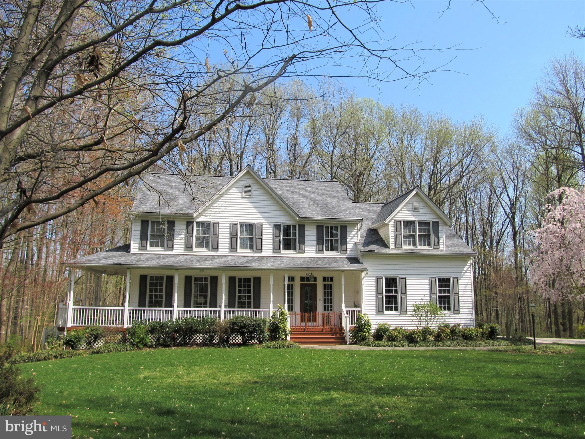 Privacy yet not seclusion is yours in this beautifully maintained, single-owner custom house surrounded but not engulfed by almost four acres of mature hardwood trees on the premier lot of its small, peaceful neighborhood in the heart of the sought-after countryside south of Annapolis. Casual elegance begins in the upgraded, beautifully appointed central kitchen with walk-in pantry and two butler pantries, all with granite and furniture-grade cabinetry, and spills into the adjoining, high ceiling family room and breakfast room, both opening to a brand new composite deck overlooking the back woods. To the other side of the kitchen beyond the foyer and wet bar are a formal dining room with large bay window and living room opening onto the side of a large wrap-around front porch equipped with a swing where many lazy evenings are to be celebrated. On a side-hill setting, the entire two-story house and finished walkout basement is bathed in the light of 50 windows. The upper level contains a large primary suite with its own wrap-around seven-window sunroom, cathedral ceiling, lofted closet, and five-piece primary bathroom. The guest bedroom and two lesser bedrooms down the hall bookend a spacious, sound-insulated laundry room with sewing nook. The fifth bedroom is on the lower walk-out level and opens by private door to a bluestone patio that also serves the cinema grade $15,000 projection theater with 113” screen and auxiliary remote 90” screen. The ground level area is served by a separate kitchenette. This level is ideal as an office suite (its current use) or in-law suite. The present owners have made over $70,000 in improvements in the past year, including new roof, Renewal by Anderson doors, large new deck, granite fireplace surround and new hardwood floor, concrete area driveway with two turn tabs and walk to an Amish-built tractor shed, and much more. The home offers loads of taken-for-granted amenities too numerous to list, such as radio/intercom and central vac with power dust pans. Behind the house are a quarter mile of owner-built pathways wide enough for a riding mower and leading to, among other things, a fire pit for s’mores and picnics and a stream. A property like this rarely comes onto the market at such an affordable price. Come take a look!