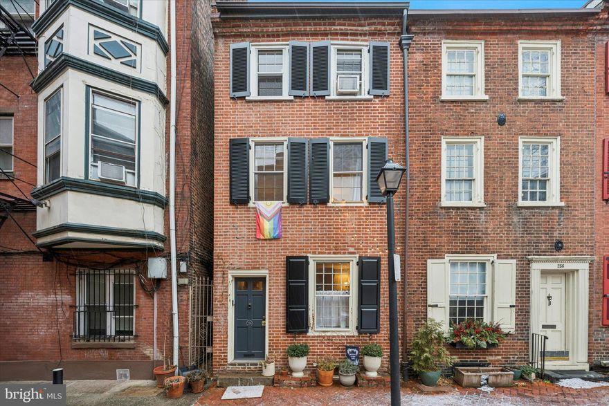 Tucked away on one of Washington Square West’s most picturesque cobblestone lanes, this 1850s brick 
townhome marries period charm with tasteful updates. Step inside to a sun‑splashed living room featuring 
soaring ceilings, handsome built‑ins, gleaming hardwood floors and a gas fireplace set in an original 
mantel—an inviting focal point for gatherings. Beyond, a thoughtfully renovated kitchen boasts custom 
maple cabinetry, granite counters, a glass‑tile backsplash and a suite of stainless‑steel appliances, 
creating a seamless blend of old‑world warmth and modern convenience. Upstairs you’ll find two well‑proportioned bedrooms, each with large windows and its own gas fireplace, adding both character and warmth. The full bath on the second level has been refreshed with contemporary fixtures while respecting the home’s classic aesthetic. A top‑floor bonus space—currently used as a primary bedroom or studio—features vaulted ceilings and ample storage. Out back, a private brick patio offers a peaceful retreat for morning coffee or alfresco dining amid the city’s hustle and bustle. Located steps from cafes, boutiques and leafy parks, this residence delivers the quintessential Philadelphia rowhouse experience on a tranquil, tree‑lined block.