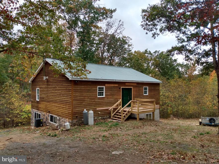 Cabin in the Woods, setting on 5 wooded acres and overlooks several stream fed koi ponds. The unique interior layout is open in design, great room with many large windows & woodstove, one very large bedroom with connecting bath on the main floor.  The lower level is partially finished, with two additional bedrooms, full bath and huge rec room, (all framed in with electric and plumbing).   High ceilings throughout the entire home add to the spaciousness. Some work still to be completed, and sold AS-IS, but still a great value. Add the Cacapon River access lot and this could be the mountain escape you've been waiting on.