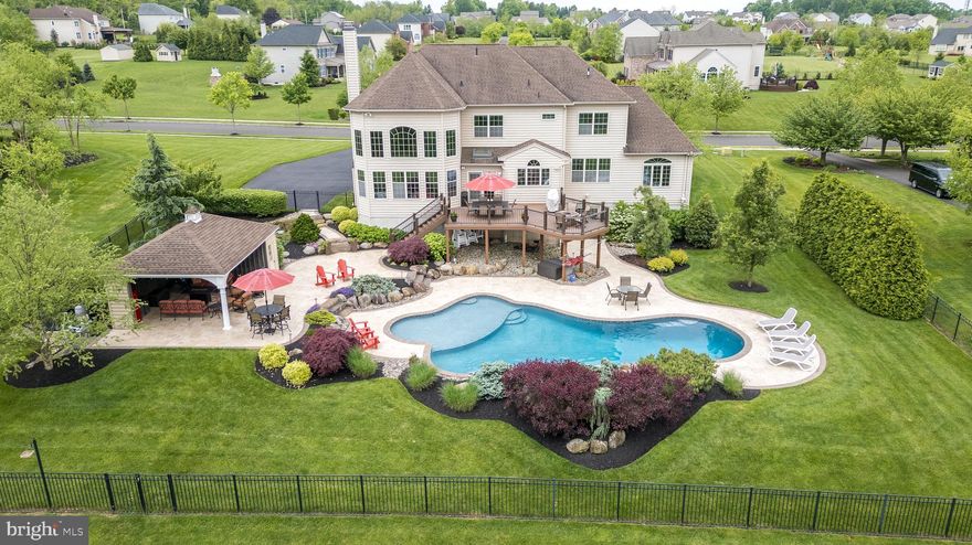 Nestled on a 1.33 acre lot in the heart of Bucks County's picturesque Ashland Meadows, a sought-after Toll Brothers neighborhood in Hilltown Township. This stunning 4 bedroom 3 ½ bath Colonial is an entertainer's paradise, boasting sensational curb appeal with a full stone façade and enchanting LED landscape lighting. This impeccable residence has a flowing layout that exudes warmth and sophistication. The 2-story foyer welcomes you with its grandeur, while 9-foot ceilings and rich hand-scraped wood floors grace the main level, creating an inviting ambiance throughout. The main level features a study off the foyer, a tranquil space with a view of the neighborhood. The Conservatory  with custom Travertine flooring and glass double doors is wrapped in windows. All windows and doors throughout the home are tinted to preserve furnishings. The Living Room and Dining Room are elegantly defined by decorative pillars. The heart of the home lies in the sunny, eat-in kitchen, which showcases stainless steel KitchenAid appliances, granite countertops, and a custom tile backsplash. The breakfast area is open to the Family Room, boasting a soaring coffered ceiling and a magnificent 2-story floor-to-ceiling stone fireplace, perfect for gatherings with loved ones. Retreat upstairs to the grand primary bedroom suite, complete with a sitting area, enormous walk-in closet, and a luxurious primary bathroom featuring a cathedral ceiling, dual vanities, a 2-head shower, soaking tub, and private water closet. Three additional bedrooms are generously sized and offer walk-in closets. A full bathroom is shared by the secondary bedrooms, with a separate sink and private access into one of the bedrooms. The additional 1300+ sq ft walk-out lower level is an entertainer's delight adding an additional  featuring decadent finishes including rustic barnwood and stone walls, sliding barn doors, and a curved granite 2-tiered wet bar equipped with a dishwasher, full-size refrigerator, beverage cooler, and wine rack. A game room, media area with a 100” Dimplex fireplace, and a full bathroom complete this fabulous space. Step outside to the ultimate outdoor oasis, where a heated inground saltwater pool with a 2-sided waterfall awaits, surrounded by Travertine hardscaping and decorative aluminum fencing. Relax on the sun shelf or retreat into the 2-sided cabana/pool house with storage, ceiling fan, and TV with soundbar. Additional highlights of this exceptional property include an oversized 3-car garage, main-level laundry room, surround sound stereo system, and ADT security system. Just 3 miles to Peace Valley Park to enjoy, biking, hiking and boating. Don't miss this rare opportunity to own a truly extraordinary home that offers the perfect blend of luxury, comfort, and entertainment!