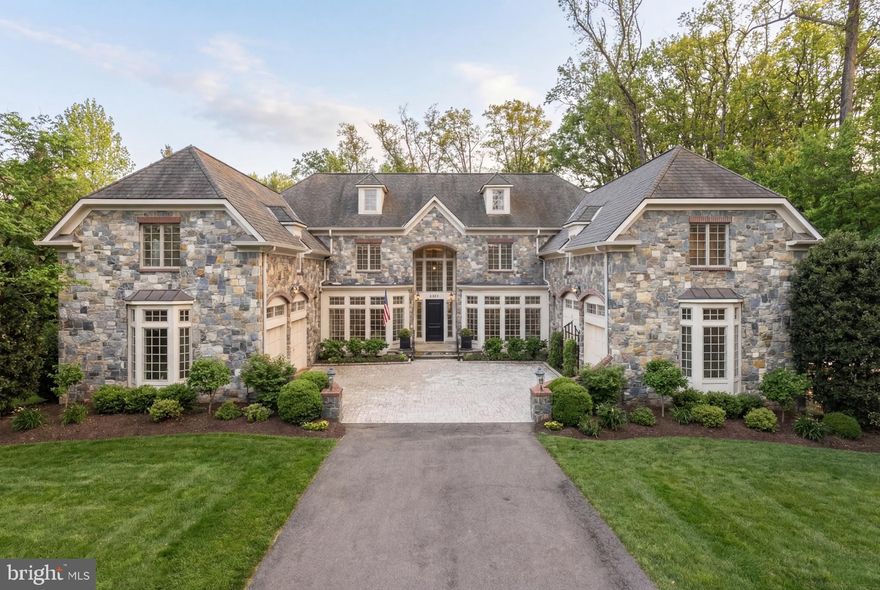 Please note:  Deadline for offers is 6 pm EDT, Saturday, March 21st.  Few homes in one of McLean's most coveted enclaves offer this combination of scale, sophistication, and a setting that feels genuinely private. Set on nearly three-quarters of an acre in highly sought after Langley Forest, this thoroughly updated English-style residence delivers close to 9,500 square feet across four finished levels — with eight bedrooms, six full baths, and two half baths — architecture and volume that announce themselves the moment you arrive and deepen with every room you enter.

The motor court sets the arrival sequence. Two flanking garages frame the approach with the kind of symmetry that belongs on a different continent, while extensive professional landscaping — layered plantings, mature specimen trees, considered hardscaping — carries that intention all the way to the rear. The backyard is fully fenced, a large and genuinely private expanse that functions as a true outdoor room.
Inside, the scale is immediate. Soaring ceilings throughout the home — vaulted in the family room, grand in the formal rooms, generous on every level — give the interiors a presence that photographs struggle to capture. Custom millwork, gleaming hardwoods, and refined finishes establish the tone in the living and dining rooms flanking the entry foyer. The family room commands attention with its vaulted ceiling and oversized windows that pull the landscape in. The gourmet kitchen is the working heart of the home — light-flooded, generous in counter and cabinet space, with a breakfast area that opens directly to the rear terrace and screened porch. A library with a fireplace anchors the north wing.

Eight bedrooms across four levels offer flexibility that few homes can match. The main level suite handles guests or multigenerational living without compromise. The upper-level primary suite is a destination unto itself — sitting room, custom cherry walk-in closet, and a spa bath with separate vanities. A third suite provides an additional private retreat ideal for extended family or a dedicated executive workspace. The lower level completes the picture with a recreation room and wet bar, wine cellar, home theater, exercise room, and sauna.

Minutes to Tysons, Georgetown, and Dulles. Langley High School pyramid.