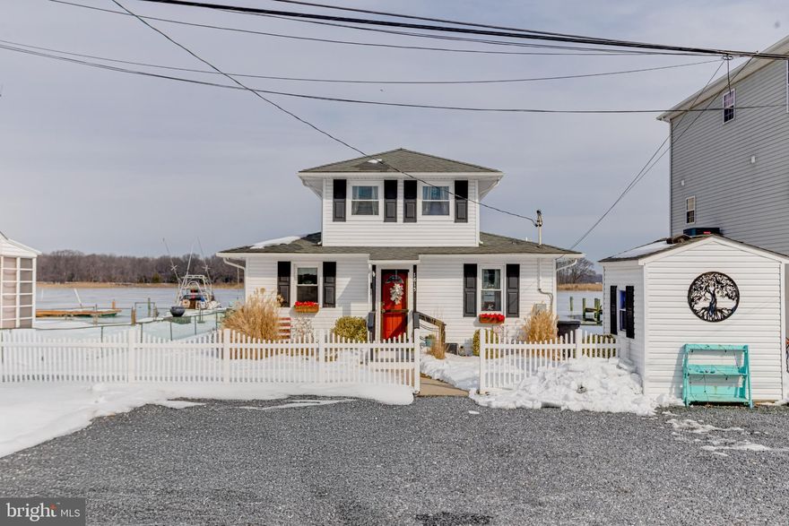 From the moment you arrive, this waterfront home captures your heart. As you pull up, you’re greeted by a charming cottage setting, framed by a beautiful white picket fence, manicured lawn, and soft accent lighting that creates a warm and welcoming atmosphere. A spacious six-car parking pad offers plenty of room for family and guests, while a Level 2 EV charging station at the front of the driveway adds modern convenience. Step through the front door and immediately feel at home. Inside, you’ll discover a cozy, quaint cottage ambiance paired with thoughtful upgrades. The open floor concept creates a bright and inviting flow, featuring premium vinyl plank flooring, stainless steel appliances, a built-in refrigerator, and generous countertop space—perfect for cooking, hosting, and gathering. The living area centers around a cozy electric fireplace set against a stunning shiplap wall with a TV mount, making it the ideal space to relax and unwind. A convenient full bathroom and main-level bedroom provide comfort and accessibility for guests or family. Upstairs, you’ll find two spacious bedrooms and a charming, well-appointed bathroom, creating a peaceful retreat after a day on the water. Outside, this property truly shines. The backyard is designed for making memories, featuring a beautiful fire pit and pergola—perfect for cozy bonfires, crisp evenings, and quality family time under the stars. A built-in canoe rack provides easy access to waterfront adventures, while a dedicated storage shed with electricity keeps lawn equipment and outdoor tools organized and protected from the elements. The private pier and bulkhead, approximately seven years old, are thoughtfully designed for both function and enjoyment. The pier offers electric service, steps leading directly into the water, and a generous 14 foot-wide landing at the end. With approximately five to six feet of water depth at the end of the pier, it is ideal for boating, fishing, crabbing, and waterfront recreation. With three bedrooms, two full bathrooms, breathtaking views, and updated pier, and and exceptional outdoor amenities, this fully renovated waterfront cottage offers more then a home; it offers a lifestyle. As an added benefit, flood insurance is approximately $678 per year, providing peace of mind and affordability. Peaceful. Inviting. Truly unforgettable.