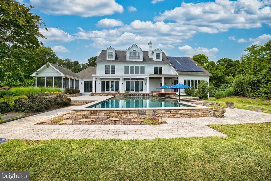 This stunning waterfront retreat sits on over 5 acres just 15 minutes from St. Michaels and is designed with flexibility in mind—perfect for year-round living, hosting guests, or simply spreading out and enjoying the Eastern Shore lifestyle. The property includes both a main residence and a fully renovated guest wing, and each features a ground-floor primary suite.

The main home offers panoramic water views, spacious en-suite bedrooms, an oversized pantry and laundry room, and a versatile third-floor space ideal for a home office or creative studio. The second level features an additional primary suite and guest room, both with updated baths and large walk-in closets. An interior breezeway past the 3-car garage leads to a private wellness wing complete with an Endless Pool Swim/Spa, fitness zone, and a cozy lounge with a fireplace and media setup.

The guest house includes a stylish kitchen, open-concept living and dining areas, a screened porch, its own laundry room, and a ground-floor primary suite. Upstairs, you’ll find two more bedrooms, a shared living space, and an updated full bath.

Outside, enjoy over 300 feet of pristine shoreline, a private dock with kayak and paddle board access via private ramp, a saltwater pool with an integrated jacuzzi, and wide-open water views. Thoughtful sustainable features include geothermal heating and cooling and a solar energy system.

This property blends comfort, privacy, and thoughtful design in a prime waterfront location near both St. Michaels and Easton—ideal for those looking to enjoy the best of the Shore year-round.