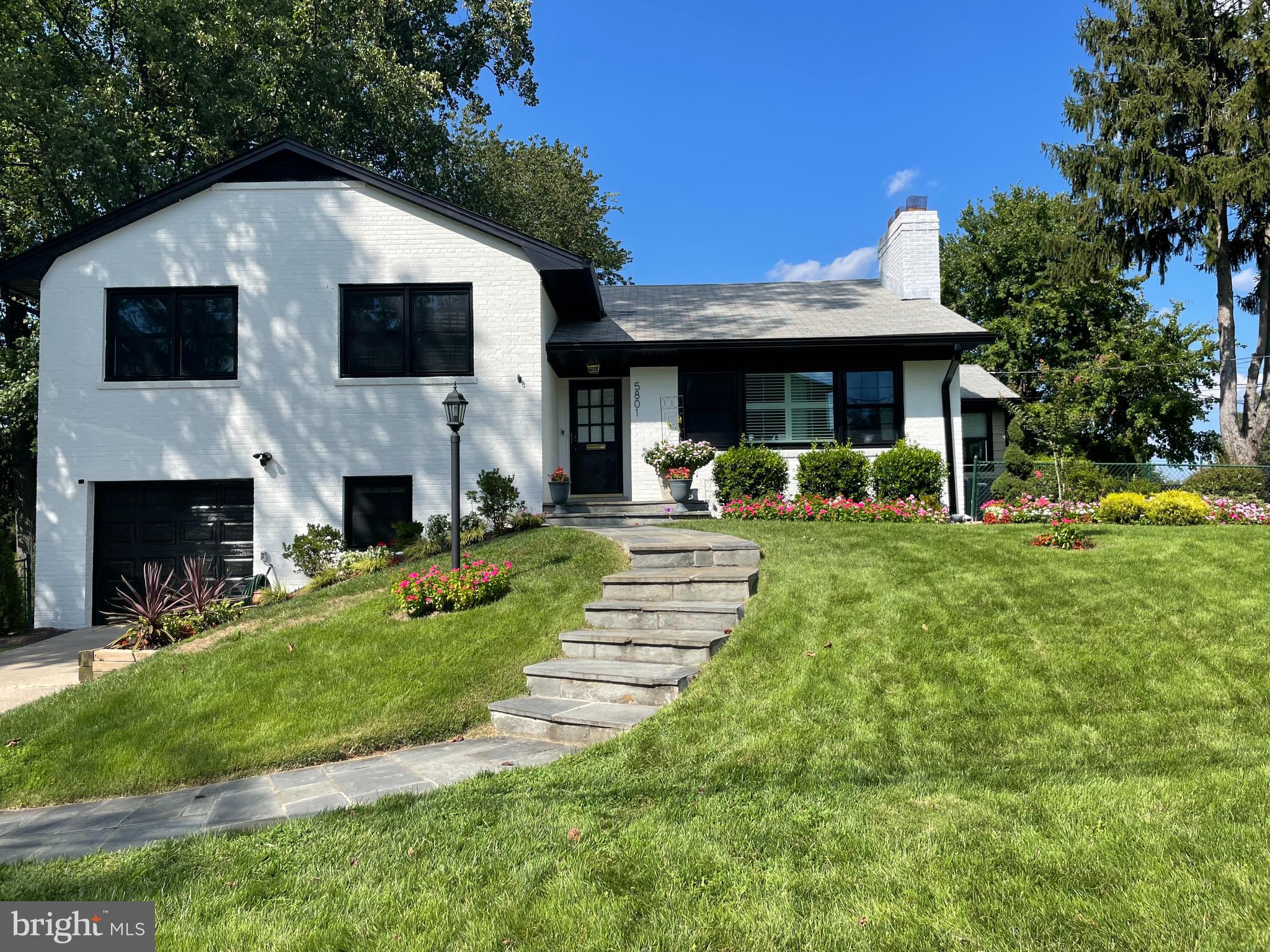 Welcome to 5801 Ogden Ct in Bethesda, a spacious and beautifully remodeled 4-level split home, expertly maintained, on a prominent corner lot, offering exceptional indoor-outdoor living and modern comfort. Fully fenced and gated with gorgeous landscaping, garden beds, and an extra-large patio ideal for entertaining, this residence combines timeless style with thoughtful upgrades.
Step into the elegant main level, featuring a gracious foyer, sun-filled living room with a fireplace, and updated windows with plantation shutters. The formal dining room opens to a sunroom/den with a mini-split system and sliding glass doors leading to the expansive patio. The updated kitchen offers beautiful countertops, gas cooking with hood vent, pantry, and pullout drawers for maximum functionality.
The upper level includes two generous size bedrooms and a gorgeous renovated full bath, while the primary suite features a walk-in closet and a remodeled en-suite bath with glass shower doors. A walk-up attic provides an abundance of additional storage space.
The lower level boasts a guest bedroom, a large and inviting family room with a custom wall of built-ins, and ample room to relax or work from home.
The finished basement level includes a spacious rec room with a fireplace, a half bath, laundry area, mechanical room, and extra storage.
A one-car garage, fully enclosed yard, and lovingly landscaped grounds complete this versatile and inviting home. Ideally located close to downtown Bethesda, I-495, and DC, and thoughtfully maintained, this property is ready to welcome its next chapter.