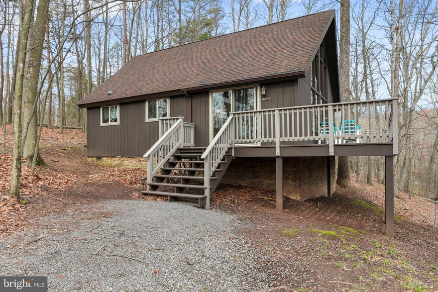 Come and enjoy this quite peaceful location at The Woods. Beautiful 1.12 acre wooded lot with wet/dry stream at rear of property and lots of privacy! This A-frame/chalet style home comes with a unique interior Scandinavian design that consists of clean, simple lines with minimalistic decor that offers a bright and airy feel throughout. Window wall of glass, cathedral ceilings and gorgeous pine hardwood floors. Cozy up in the great room by the woodstove, which sits in front of the rustic stone facade. Enjoy playing games or watching movies in the loft that overlooks the great room and has stunning views of the wooded lot. Relax with family and friends on the huge 8x30 open deck with views down the hill to the creek below. The owners have taken so much pride in their home by adding a stone front on the block foundation & fireplace facade on the block foundation & fireplace chimney. In 2017 they added new windows and added the primary bedroom/bath. The exterior was painted in 2022. Selling furnished/turn key. Class B Family membership available with a $3,150.00 initiation fee additional.