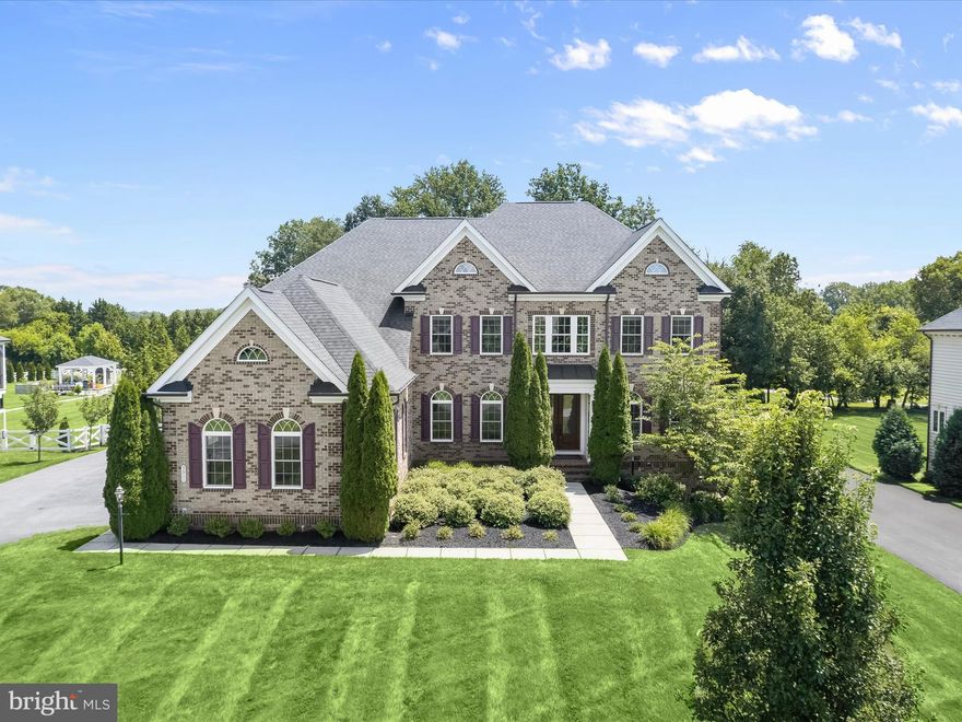 This absolutely impeccable NV Homes Clifton Park model, custom built and lovingly maintained by its original owners, offers more than 8,000 square feet of luxurious living space across three finished levels perfectly situated on over an acre in the sought-after Greenberry community. Every inch of this home reflects thoughtful design and craftsmanship, beginning with a stately exterior and continuing throughout a floor plan that combines elegance with comfort.
Step into the grand two-story foyer, where a sweeping staircase with decorative iron balusters sets the tone. Flanking the entry are formal living and dining rooms, both adorned with elegant trim details; the living room showcases a beautiful bay window, while the dining room features box wainscoting, crown molding, chair railing, and a tray ceiling for added dimension. Just beyond, a well-appointed butler’s pantry connects to the showstopping kitchen, an entertainer’s dream with sleek granite counters, tile backsplash, two oversized center islands, professional-grade appliances, walk-in pantry, prep sink, and pendant lighting. Display cabinetry and a casual dining area offer form and function, while a secondary staircase just off the kitchen leads to the upper level.
The adjacent great room captivates with its soaring two-story ceiling, arched windows, coffered detail, and floor-to-ceiling gas fireplace wrapped in custom tile. Five glamorous Restoration Hardware light fixtures and premium hardwood floors elevate the home's aesthetic even further. For everyday ease, the main level also includes a mudroom with a built-in drop zone, a spacious office with custom built-ins, a powder room, and a laundry room.
Upstairs, the private primary suite is a retreat in every sense, complete with a sitting area with fireplace, custom walk-in closet, and private balcony. The luxurious en suite bath pampers with an extended double sink vanity, soaking tub, oversized walk-in shower with dual shower heads and seating, and a water closet. Three additional bedrooms, each with walk-in closets and private baths, offer space and privacy for all.
The lower level continues to impress with a massive recreation area, custom granite wet bar with seating, and a walk-in pantry, media room with high-end projector, screen, and built-in speakers, an exercise room, a full bath, and a fifth bedroom. For golf lovers, there’s even a putting green and golf simulator to perfect your swing year-round.
Step outside to an expansive, fenced backyard with a half-court sport court, ideal for basketball, hockey, or pickleball, with a net included. The three-car side-loading garage features built-in storage and new keyless entry. A front-yard irrigation system ensures a lush lawn year-round.
Built with no expense spared and every upgrade imaginable, this home is a rare combination of elegance, comfort, and unmatched functionality.