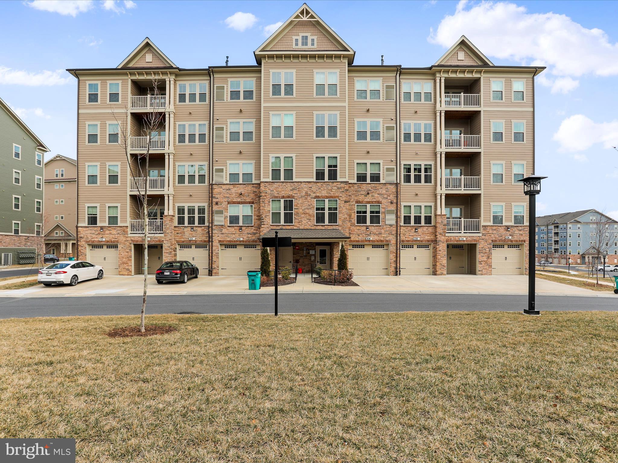 Welcome to the Woodlands, Frederick’s outstanding 55+ community. This gorgeous corner unit condo, Chambord Model, with 1489 square feet of high-end finishes, has two large bedrooms, two large bathrooms, and is part of a vibrant community with 5-star amenities and events. Enjoy one-level living, and a beautifully thought-out open floor plan with an abundance of natural light. The gourmet kitchen with a 2-tier island has a custom tile backsplash, 42-inch kitchen cabinets, separate pantry, and stainless steel appliances. A private covered porch with western views is the perfect spot for morning coffee, plants, a glass of wine, cocktails, and brilliant sunsets all year long. Upgraded Vinyl Luxury Flooring, luxury tile in the bathroom, quartz vanity tops and upgraded bathroom mirrors are but a few of the special features. A bonus room off the guest room is a perfect space for an office, study, sewing room, or reading room. This lovely home is just steps from the elevator, has a one-car garage with interior locked access, and plenty of guest parking. You'll quickly feel the sense of community and enjoy almost endless activities and amenities. The Woodlands is full of social clubs, social events, athletic classes, walking trails, pickleball, tennis courts, a gym, a swimming pool, a clubhouse, and so much more. The amenity photos showcase only a fraction of what this community has to offer. This home is turnkey and perfectly proportioned. And, you never have to shovel snow again! Restaurants, retail, a library, parks, and all things Villages of Urbana Marketplace are just a quick 20-minute walk or even quicker drive; downtown Frederick is minutes away by car.
