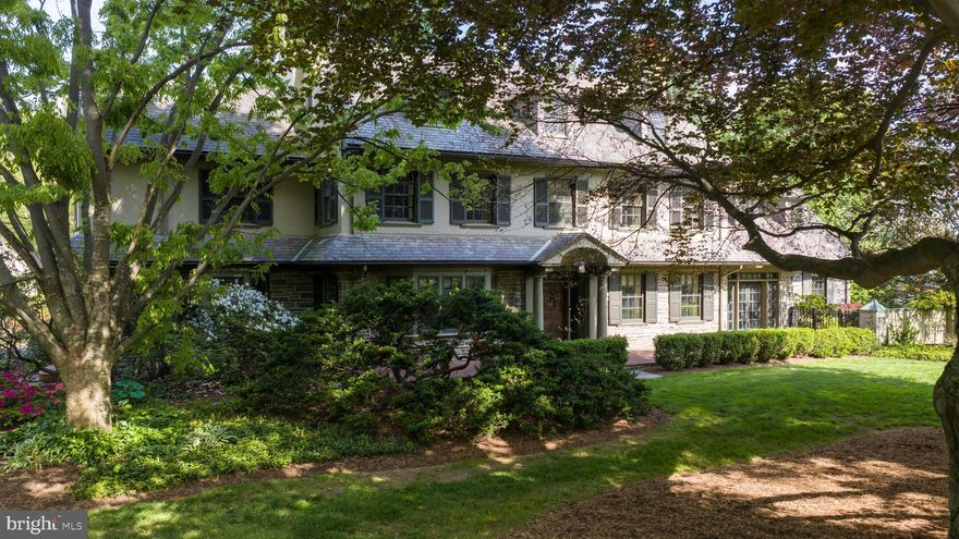 Built in 1927 to architectural designs attributed to C. Emlen Urban, with grounds laid out by Thomas W. Sears, Breeze Hill is a rare survival of an early-twentieth-century Lancaster estate where house and site were conceived as a single composition. The 1.54-acre plan, stone walls, and original circulation patterns remain intact. The house was built to substantial standards: exterior walls of three courses of solid brick with steel beam structural support, finished in stucco and stone beneath an original Peach Bottom slate roof. The foyer opens with heartwood flooring accented by inlaid tile, a grand staircase, crown molding, chair rail, and wainscoting. A powder room sits beneath the staircase. The formal dining room, entered through paned French doors, centers on a large bay window with a marble-surround fireplace framed by a window and a glass-front built-in. A connecting hallway with tile flooring and beadboard wainscoting leads to a butler's pantry with sink and built-in cabinetry, with access to a secondary staircase. The kitchen has granite countertops, extensive cabinetry, Sub-zero refrigerator and wine fridge, Thermador double ovens and gas cooktop, cast-iron sink, and a fireplace with original mantel - uncommon in a working kitchen. A bay window forms the breakfast nook; French doors open to the exterior. To the right of the foyer, a grand sitting room features hardwood flooring, crown molding, chair rail, recessed mantle art lighting, and a striking marble fireplace with detailed trim and wall sconces. French doors on either side open to a sunroom with brick tile flooring, floor-to-ceiling paned doors with transoms, stone accent wall, and built-ins. The sunroom flows into a wet bar with copper countertop, wine refrigerator, and vaulted ceilings. Beyond, the family room rises to cathedral ceilings with paneling, French doors flanking a stone fireplace, and upper-level windows. The main staircase ascends past a large window to a second-floor landing with sitting room or office and hardwood flooring, crown molding, and wainscoting. The primary suite includes a marble fireplace with finely milled mantel and a walk-in closet with custom built-ins; the recently renovated en-suite bath has a soaking tub, glass-enclosed shower, double vanity, and vaulted ceilings. A laundry room with built-in cabinetry sits nearby. Additional bedrooms feature hardwood flooring and built-ins, served by a full bath with walk-in shower and soaking tub. The third floor is original to the house and fully habitable: hardwood flooring, architectural millwork, vaulted ceilings, and a full bath with clawfoot tub. Currently configured as library and art studio with cedar-lined storage. Major systems have been comprehensively updated and documented under current ownership: full-house rewire to modern 200-amp service with integrated smart dimmers by Stephen M. Daniels, 2023; high-efficiency natural gas boiler with four-zone hydronic distribution by Red Truck, 2024; interior plaster and ceiling restoration; and new pumps and heater for both an in-ground pool and spa. The 1.54-acre grounds were laid out by Thomas W. Sears and retain the stone walls, mature plantings, and circulation patterns of the original plan. A circular driveway centered by a brick island and framed by wrought iron fencing establishes the approach. The rear grounds are anchored by a heated Gunite pool and spa, professionally maintained, with a stone patio and brick outdoor fireplace, a raised patio with dual changing rooms, in-ground surround speakers, and flagstone pathways connecting the spaces. A three-car garage with carriage house above sits at the end of the drive. Ideally situated along Lititz Pike, this property offers excellent visibility and easy access to major routes, Lancaster City, and nearby shopping, dining, and everyday amenities, making it a prime spot for both accessibility and connectivity.
