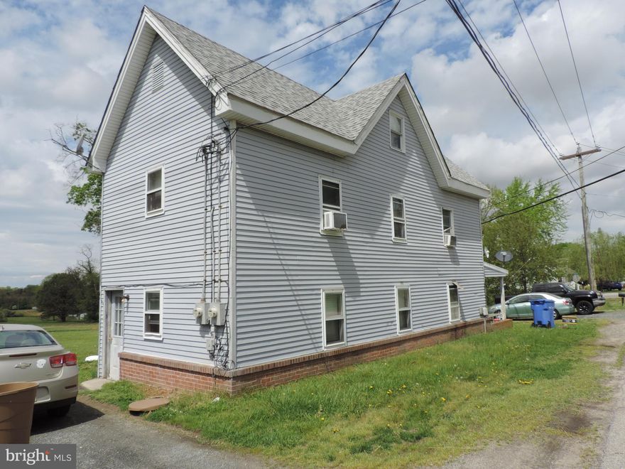 Two apartment dwelling sited on 2.51 acres zoned Village offers town water/sewer with units served with separate electric meters.   The large spacious open area behind the dwelling offers great potential for possible development ...details for same need to be researched with county planning and zoning.