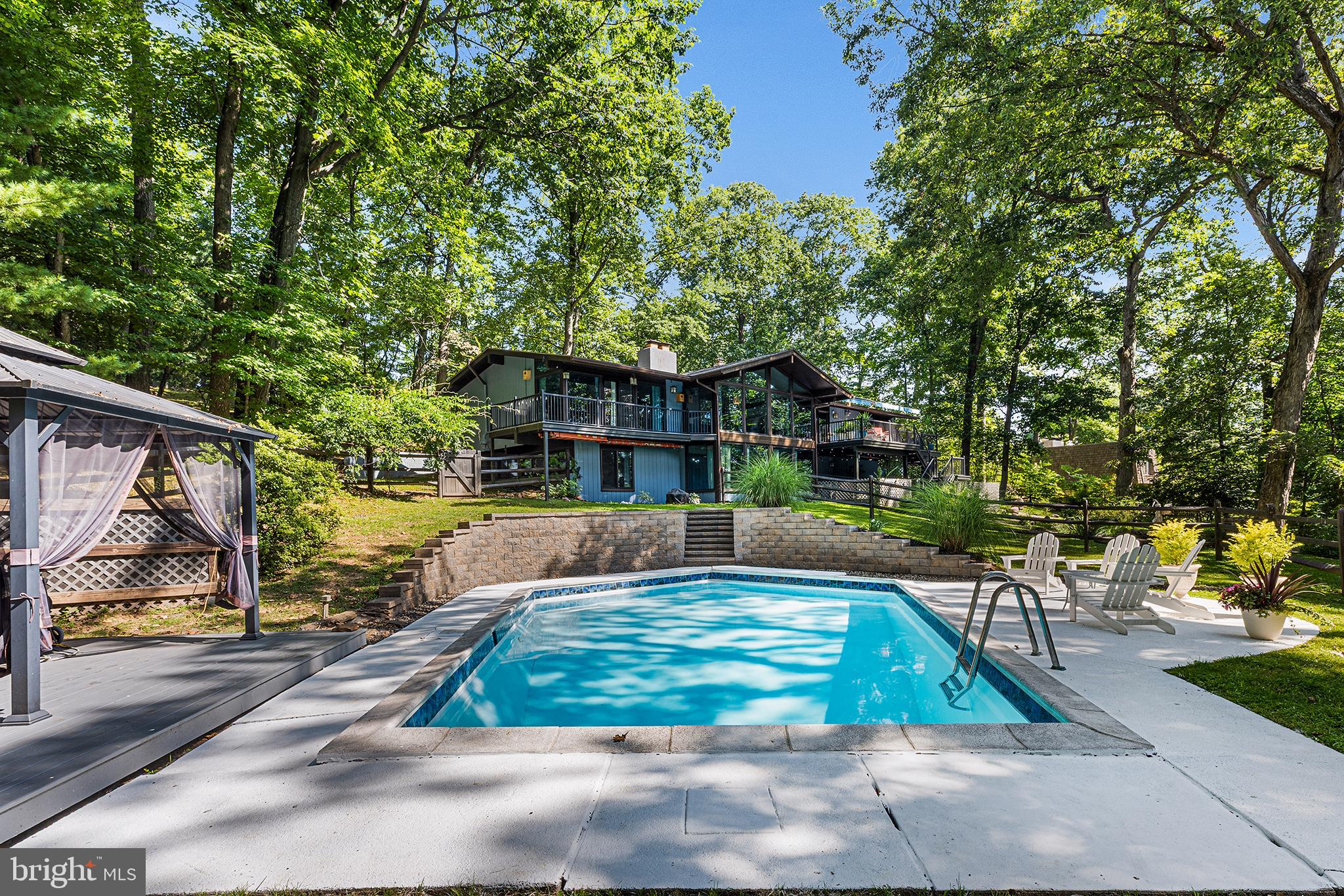 Although you will feel like you are miles away from the hustle and bustle of everyday life, it takes just minutes to get to everything from this stunning 4 bedroom, 2.5 bathroom McElroy contemporary home which is nestled on a private one-acre lot on a quiet cul-de-sac. This midcentury modern house offers picturesque natural views from every room in the home, welcoming the outdoors inside, and a wonderful open floor plan which is spacious and functional. Upon entering, you are captivated by the vaulted ceilings and large windows which allow the amazing view and natural light to flow into the home. The updated kitchen offers custom cabinetry, tile backsplash, Bosch appliances and a center island/breakfast bar, as well as a casual dining area. The flexible main floor is perfect for entertaining or enjoying intimate gatherings, featuring a dining area, family room with wood fireplace and entertaining area. The main floor also offers a spacious Primary Bedroom with a walk-in closet and updated ensuite bathroom with soaking tub. A true bonus are the sliding doors which lead from the Primary Bedroom to your personal outdoor balcony, which is perfect for stargazing. In addition, sliding doors from the main level lead to a balcony which overlooks the rear yard and in-ground pool. A convenient half bath completes the main level. The lower-level offers three additional spacious bedrooms, a full bathroom, plus a beautiful entertainment room with a built-in speaker system, wood fireplace and sliding doors to a large balcony overlooking the natural backyard landscape. The laundry room and access to the two-car garage complete the lower-level. The large private rear yard boasts a beautiful in-ground salt water pool and offers plenty of space for your firepit or garden. Updates to the home include new exterior painting, new UV protection windows and sliding doors, new sidewalks and stairs to the front, updated kitchen and bathrooms, and new A/C (2024). This is a special, one of a kind property! Book your appointment today!