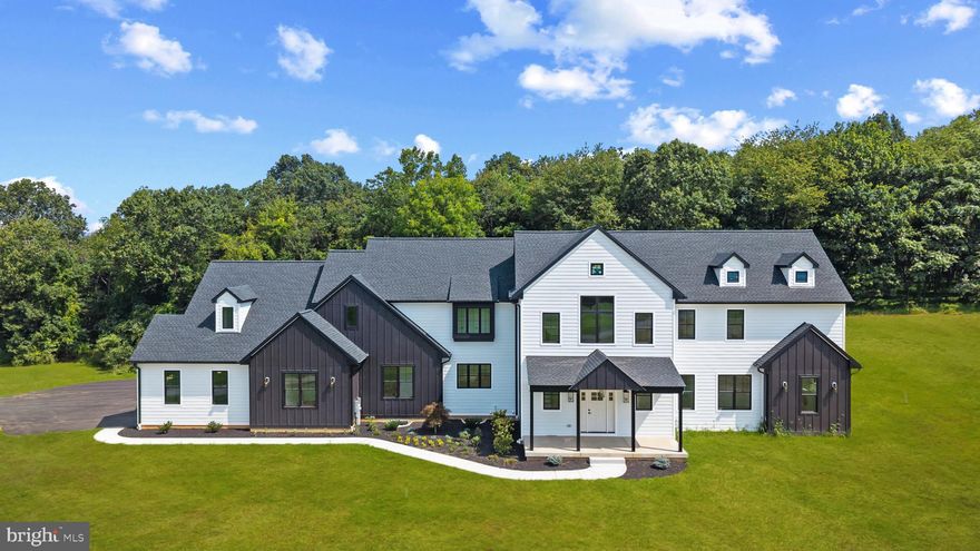 Discover a remarkable new custom home by Sweeney Builders, perfectly nestled on more than four acres of wooded privacy. Thoughtfully crafted with enduring materials and refined design, this residence offers a rare blend of luxury, serenity, and modern livability.  White oak floors and soaring cathedral ceilings welcome you into interiors filled with natural light. The main level is designed for today’s lifestyle—open, airy, and ideal for effortless entertaining. The living room, dining area, and chef’s kitchen flow together beautifully, anchored by a sleek gas fireplace that creates a sense of warmth and sophistication. The kitchen is both functional and refined, featuring a suite of Viking appliances including an 8-burner range, wine refrigerator, and prep sink. Quartz countertops, brass fixtures, and soft-close Candlelight Cabinetry add a bespoke touch, while the expansive butler’s pantry—with a second Viking refrigerator and dual warming drawers—makes hosting seamless. A flexible office or fitness room, a mudroom, and access to the three-car garage complete this level. The main-floor primary suite serves as a private retreat, with French doors opening to the peaceful backyard and an adjoining sitting room ideal for an office or dressing space. The spa-inspired bath offers a soaking tub, rain-head shower, dual sinks, and a generous walk-in closet, while a dedicated laundry area adds convenience. Upstairs, an airy family room overlooks the main living space below, offering the perfect spot for relaxed gatherings. Four additional bedrooms provide versatility—two share a Jack-and-Jill bath—and a second laundry room enhances everyday ease. Constructed with Hardie Plank siding and Marvin windows and doors, the exterior is timeless and built to last. The expansive backyard invites endless possibilities—imagine a pool, gardens, or an outdoor kitchen—while the unfinished lower level awaits your personal touch for a theater, gym, or in-law suite. Set amid the natural beauty of Finksburg and just minutes from Glyndon, Westminster, Liberty Reservoir, and I-795, this home offers privacy, comfort, and understated luxury. A place where craftsmanship, setting, and design come together in perfect harmony.