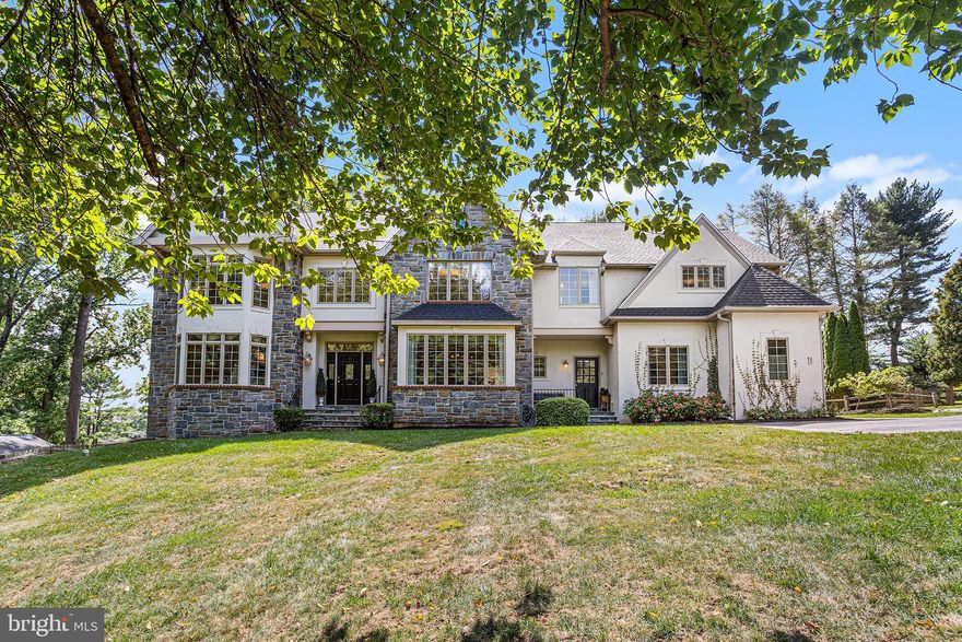 Set back from the road on a lush, private lot along one of Newtown Square’s most coveted stretches, 3408B Goshen Road radiates sophistication and bespoke luxury. This distinctive stone-front colonial commands attention with nearly $200,000 in thoughtful upgrades—showcasing a beautifully remodeled kitchen, designer lighting, artisan millwork, and custom built-ins. Step inside a dramatic two-story foyer and immediately feel the grandeur as you enter the gracious living room. Here, a striking marble gas fireplace is paired with a wall of soaring windows dressed in custom drapery, creating a light-filled sanctuary ideal for both intimate gatherings and grand entertaining. Across the foyer, the formal dining room captivates with detailed ribbon-inlay hardwood floors, elevated lighting, exquisite millwork, and prized front-yard views. At the heart of the home, the expansive, newly upgraded eat-in kitchen and great room offer the ultimate setting for family living and lavish entertaining. The chef’s kitchen boasts freshly painted custom cabinetry, all-new high-end appliances, a stunning quartz slab countertop and backsplash beautifully accented by a Greek key mosaic marble, and a massive center island with a secondary oven and bar seating. The sunny breakfast room seamlessly transitions into the great room, where custom built-ins, a gas fireplace, and oversized windows enhance the sense of volume and comfort. A sun-drenched home office, dual powder rooms, and a multipurpose secondary foyer with a laundry-mudroom provide everyday convenience and direct access to the oversized three-car garage—offering a seamless flow for busy, modern lifestyles. Upstairs, newly installed plush carpeting, elegant crown molding, and designer fixtures add a sense of refinement across every inch of the landing and bedrooms. The spectacular primary suite offers a tray ceiling, an inviting private sitting lounge or closet, and a spa-like ensuite bath featuring soaring vaulted ceilings, a walk-in glass shower, soaking tub, private water closet, and an additional walk-in closet. Four additional spacious bedrooms include one with its own lounge area and custom built-ins, while two chic jack-and-jill bathrooms offer generous proportions and timeless neutral finishes. The possibilities are endless in the oversized, walk-out basement with high ceilings—perfect for designing your dream home theater, gym, wine cellar, or playroom. Step outside to a resort-style flagstone patio and sprawling, professionally landscaped, and fenced backyard—an entertainer’s paradise that’s equally suited for relaxation and play. A new roof has just been installed and comes with a transferable lifetime warranty for lasting peace of mind .Located just minutes to dining and shopping at Ellis Preserve, this home offers easy access to commuter routes and esteemed local clubs, including Radnor Hunt. With a brand-new roof and comprehensive updates throughout, this pristine, move-in ready residence seamlessly blends classic architecture with the best of today’s luxury living. Created for the discerning buyer who values both style and substance, 3408B Goshen Road truly has it all.