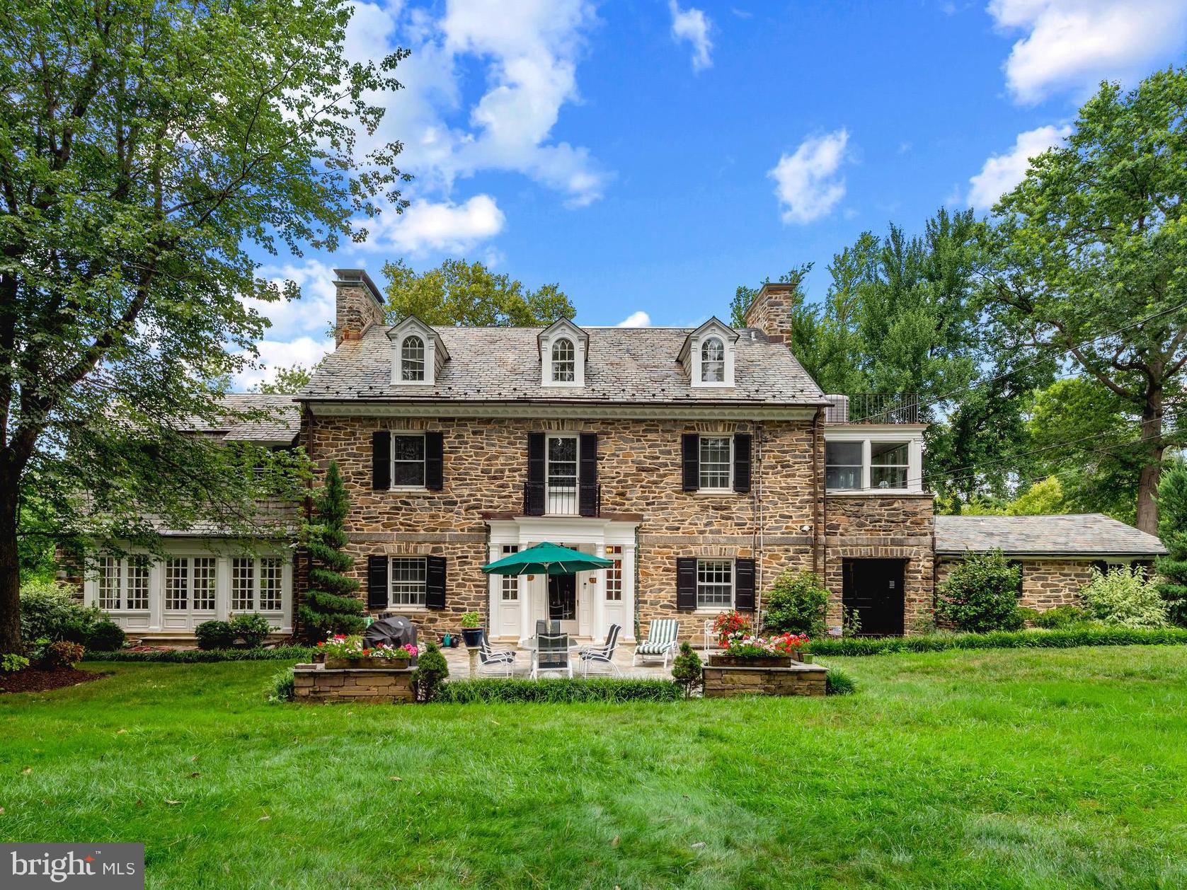 Tucked away on a quiet, tree lined street, this beautifully maintained and sweeping stone Georgian Colonial home features five bedrooms, four full and one half baths with a two car garage, and offers a rare blend of historic charm, generous scale, and modern functionality, perfectly sited on a sprawling park like, double lot. With over 6,600 square feet across four thoughtfully finished levels, this home features a seamless flow between formal and casual living spaces. The main level is designed for elegant living and effortless entertaining, with a formal living room centered around a wood-burning fireplace, a refined dining room, and a sun drenched family/sun room with a second fireplace. The gourmet kitchen is outfitted with premium appliances, a butler’s pantry, and adjacent breakfast room that opens to the rear gardens. Upstairs, the second level features a serene primary suite with a custom dressing room and spa-like bath. A paneled library with fireplace, two additional bedrooms, a bright sunroom/home office, and a full bath with Jacuzzi tub complete the second level. The third floor offers two more bedrooms, a full bathroom, and access to a charming rooftop porch. The finished lower level includes a spacious recreation room with third fireplace, a full bathroom, laundry area, two cedar closets, and ample storage and utility space. Outside, two private stone patios are surrounded by lush, mature landscaping, enhanced by custom lighting and an irrigation system—ideal for outdoor entertaining or quiet relaxation. Major updates include modernized plumbing and electrical systems, newer HVAC, professional waterproofing, a generator-ready system, CCTV and monitored security. Conveniently located just minutes from Loyola University, top hospitals, restaurants, and downtown Baltimore, this distinguished residence offers timeless appeal and turnkey comfort in one of the city’s most desirable neighborhoods.