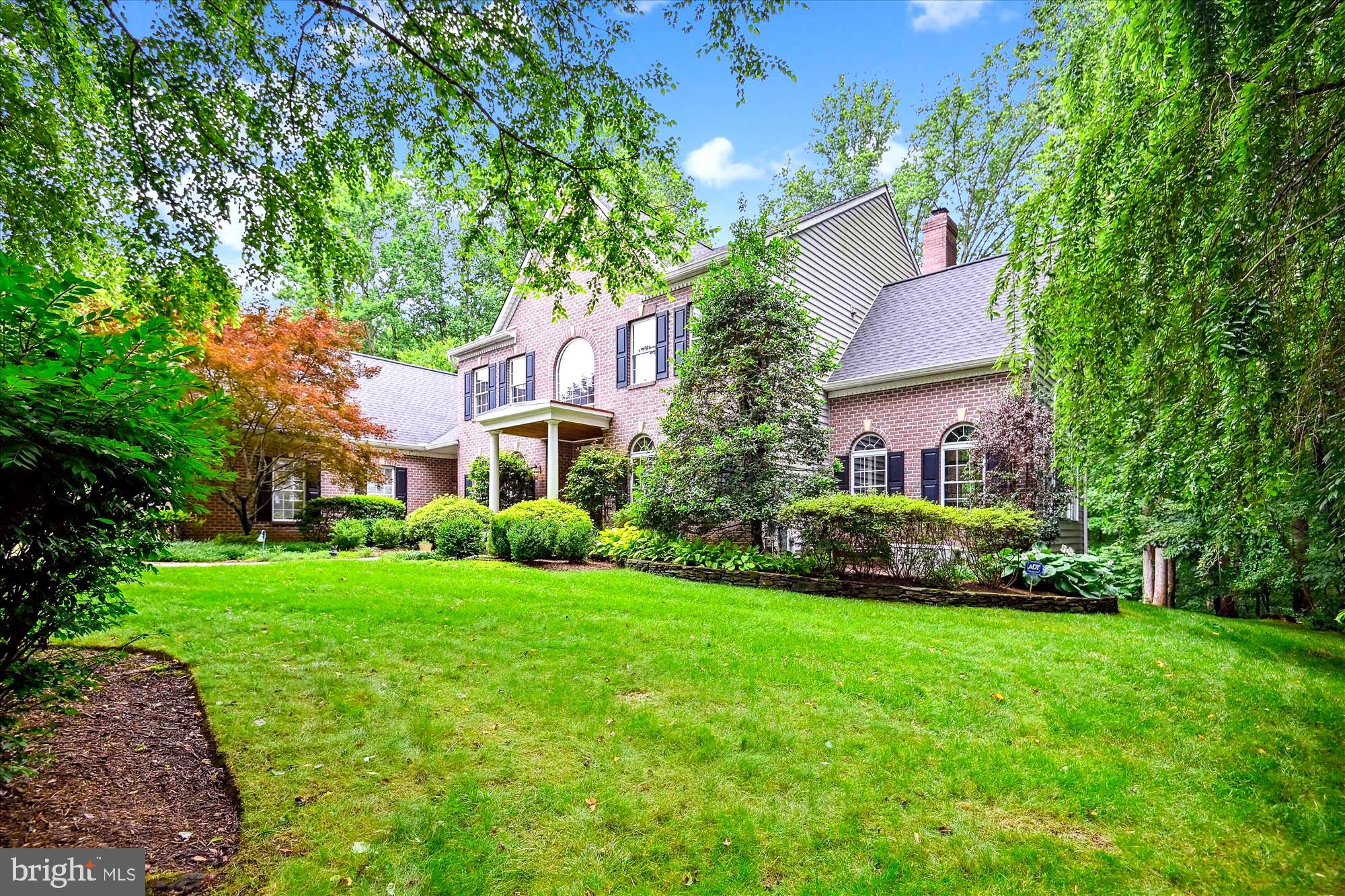 Impeccably maintained and rich with natural light, this stately brick colonial—crafted by renowned builder Rick Polm—offers timeless elegance, thoughtful design, and spaces made for everyday comfort and exceptional entertaining. The main level features a grand primary suite with gas fireplace, remote-controlled blinds, and a spa-inspired bath. A chef’s dream kitchen includes a Wolf gas cooktop, double Jenn-Air ovens, granite counters, and a spacious dining area that opens to a tiered Trex deck with private wooded views. Anchoring the home is a dramatic two-story family room with floor-to-ceiling windows and brick fireplace, complemented by a stunning cathedral-ceiling sunroom.
Upstairs, a center hallway overlooks the foyer and family room, leading to three spacious bedrooms, each with its own en-suite bath—ideal for guests or family. The expansive lower level transforms into a private retreat and entertainment haven, complete with a Key West/Hemingway-inspired bar, full-size appliances and bar seating for nine, pool and shuffleboard tables, a fully equipped gym, a luxurious state-of-the-art home theater featuring 8 custom leather reclining comfort seats, full bath, soundproof bonus room, and 2 generous storage rooms. Magnificent in-law potential with separate outside entry!
Outside, discover a beautifully landscaped backyard sanctuary featuring a custom wood-burning fireplace, elegant pergola, paver patio, ambient lighting, and a serene path that leads past a tree-lined perimeter to a gentle stream. A wide stone walkway brings you to a custom three-car side-entry garage. Offered at $1,495,000, this exceptional residence blends classic craftsmanship with modern luxury—an opportunity not to be missed.