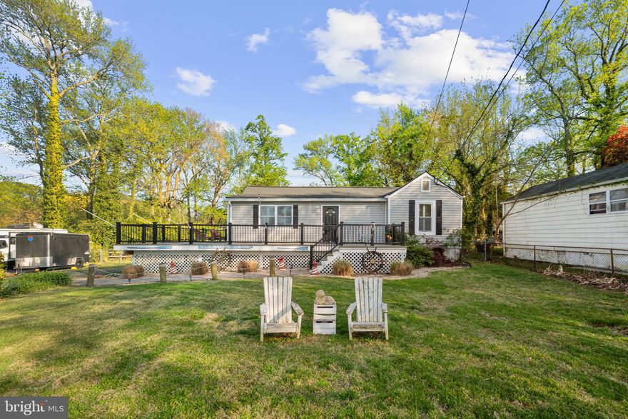 Welcome home! Nestled in this cherished waterfront community, serene views of Whitemarsh Creek greet you right from the front of the home. Whether you're looking to downsize into a low-maintenance water-oriented lifestyle or capitalize on incredible short-term rental potential, this property checks every box. This thoughtfully updated home offers an open floor plan ideal for effortless entertaining and everyday living, with rich hardwood floors and plantation shutters throughout. The generously sized living room features a charming brick corner fireplace and opens seamlessly into the gorgeously remodeled kitchen (2016), appointed with stainless steel appliances, an abundance of bright white cabinetry, granite countertops, and classic subway tile backsplash. The oversized island breakfast bar opens into the adjacent sunny dining area, where French doors lead directly to the wraparound deck for effortless indoor-outdoor living. A versatile flex space off the main living area is perfect for a home office, reading nook, or creative retreat. Both rare main level bedrooms feature elegant crown molding, plantation shutters, and ample closet space, connected by a beautifully updated jack & jill bath with a frameless glass door shower and modern finishes. The lower level offers a stunning full bath with an elegant freestanding soaking tub and floor-to-ceiling tile surround, dedicated laundry, and excellent potential for a workroom, hobby space, or additional storage. Step outside to the large wraparound composite Trex deck with remote-controlled retractable sunshade, where those front-facing water views set the perfect backdrop for sipping your morning coffee, dining al fresco, or simply unwinding as the sun sets over the creek. The fenced backyard is a true retreat as well, complete with a paver patio and brick fire pit ideal for gatherings. A storage shed and ample driveway parking large enough for parking an RV, boat, or summer guests round out the package. Major home system updates including roof (2022) with transferable lifetime warranty, HVAC (2024), water heater (2024), and windows (2015) offer true peace of mind. With Holiday Hill Marina only a block away, and both Weis Markets and Safeway conveniently within 5 miles, you'll be just minutes to charming downtown Annapolis, Mayo Beach Park, and Triton Nature Park. Quick access to Solomons Island Road, Central Avenue, Route 50, and Crain Highway. Come experience the relaxed water lifestyle this special community has to offer - schedule a private tour of your gorgeous new home today!