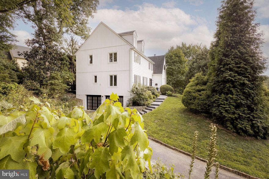 Your home search is over with this fabulous, move-in ready Chestnut Hill home near the Morris Arboretum! Set on a hill and filled with windows, this home overlooks historic stone barns in two directions and mature trees through which you can watch the sunset over the canopy of the Arboretum. Discover this hidden treehouse within walking distance to the Avenue.  Come see how the modern flow of this light-filled house can check the boxes of your housing needs.  Enter into the light filled living room; its Samoa Mahogany hardwood flooring, cathedral ceiling, a dramatic staircase, custom fireplace and two-story arched windows set the tone for the house.   The gorgeous mahogany flooring extends throughout the first floor and the dining room is open and graciously proportioned, easily seating 14. A bright and sunny chef's kitchen features a marble waterfall island, upgraded stainless appliances and a huge customized pantry.  The kitchen opens onto a family room with French doors to the partially covered deck which runs the length of the house. This home has an easy flow for intimate gatherings or lavish parties. A full bath, laundry room and another walk in pantry closet complete the main floor. The house features many designer upgrades such as lighting fixtures by Visual Comfort (powder room and dining room sconces), Curry & Company (family room)and Niche Modern (dining room), Lee Jofa and Romo window treatment fabrics and Thibaut, Anna French wallpapers and best of all Custom Closets galore! Watch the moonrise from bed in the large primary suite with its gorgeous glass solarium.  The updated walk-in rain forest shower, radiant floor, two walk-in closets make this a zen retreat in every season. Three additional bedrooms each with great views onto the gardens and large customized closets and a hall bath complete the second floor. Both bathrooms feature Porcelanosa tile. There is also potential for a 4th floor conversion of storage space to a bedroom or office that looks out to the Morris Arboretum. The lower level has large windows, a full bath and additional storage—it's a great playroom, family room, office or extra guest room.  This opens to the over-sized, heated, two-car garage with even more customized storage.  The professionally landscaped terrace, beautiful plantings, fire pit and fenced in yard (wired for Invisible Fence) create the perfect space in which to decompress from the world at large. Welcome home to 200 Hillcrest Avenue!