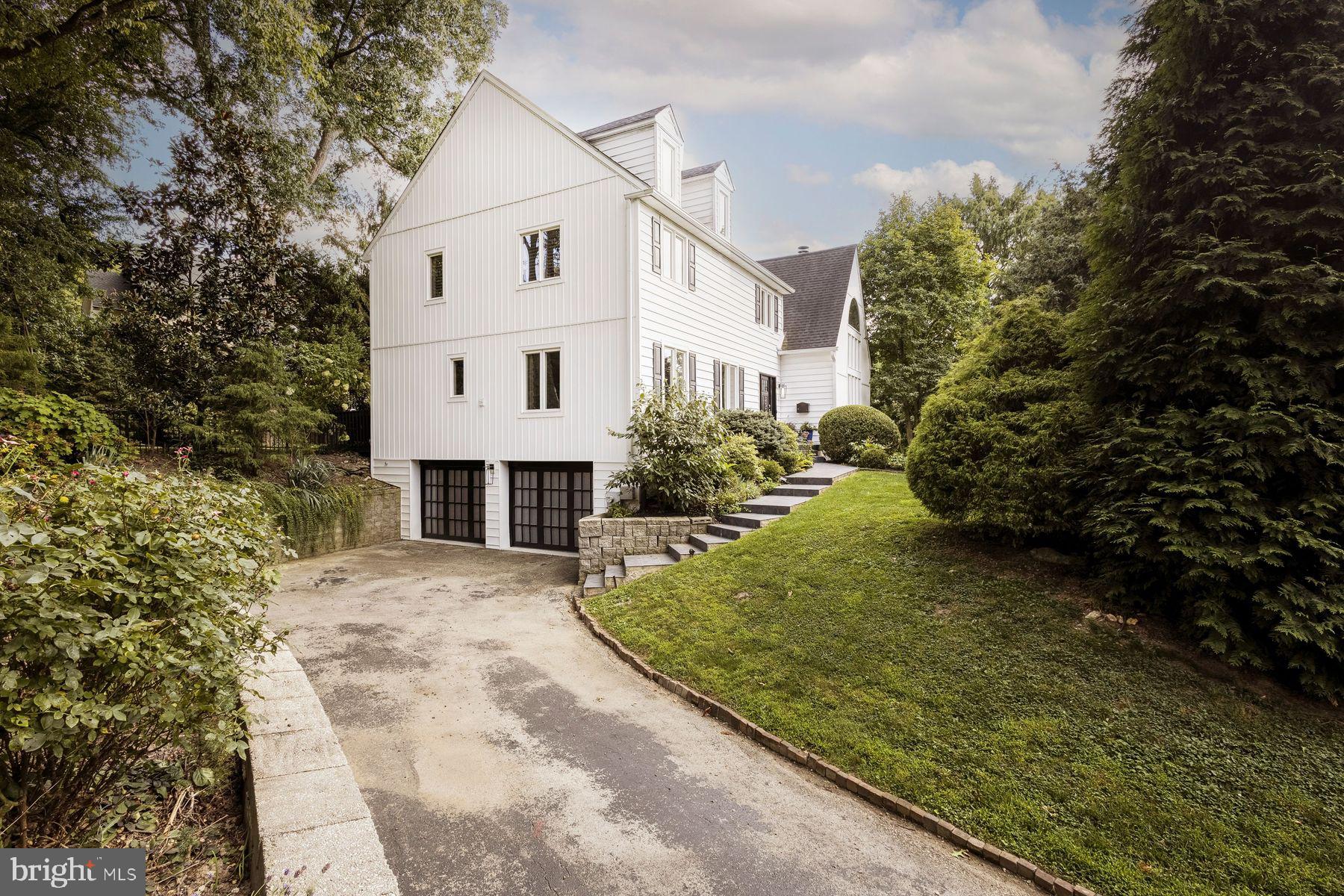 Your home search is over with this fabulous, move-in ready Chestnut Hill home near the Morris Arboretum! Set on a hill and filled with windows, this home overlooks historic stone barns in two directions and mature trees through which you can watch the sunset over the canopy of the Arboretum. Discover this hidden treehouse within walking distance to the Avenue. Come see how the modern flow of this light-filled house can check the boxes of your housing needs. Enter into the light filled living room; its Samoa Mahogany hardwood flooring, cathedral ceiling, a dramatic staircase, custom fireplace and two-story arched windows set the tone for the house. The gorgeous mahogany flooring extends throughout the first floor and the dining room is open and graciously proportioned, easily seating 14. A bright and sunny chef's kitchen features a marble waterfall island, upgraded stainless appliances and a huge customized pantry. The kitchen opens onto a family room with French doors to the partially covered deck which runs the length of the house. This home has an easy flow for intimate gatherings or lavish parties. A full bath, laundry room and another walk in pantry closet complete the main floor. The house features many designer upgrades such as lighting fixtures by Visual Comfort (powder room and dining room sconces), Curry & Company (family room)and Niche Modern (dining room), Lee Jofa and Romo window treatment fabrics and Thibaut, Anna French wallpapers and best of all Custom Closets galore! Watch the moonrise from bed in the large primary suite with its gorgeous glass solarium. The updated walk-in rain forest shower, radiant floor, two walk-in closets make this a zen retreat in every season. Three additional bedrooms each with great views onto the gardens and large customized closets and a hall bath complete the second floor. Both bathrooms feature Porcelanosa tile. There is also potential for a 4th floor conversion of storage space to a bedroom or office that looks out to the Morris Arboretum. The lower level has large windows, a full bath and additional storage—it's a great playroom, family room, office or extra guest room. This opens to the over-sized, heated, two-car garage with even more customized storage. The professionally landscaped terrace, beautiful plantings, fire pit and fenced in yard (wired for Invisible Fence) create the perfect space in which to decompress from the world at large. Welcome home to 200 Hillcrest Avenue!