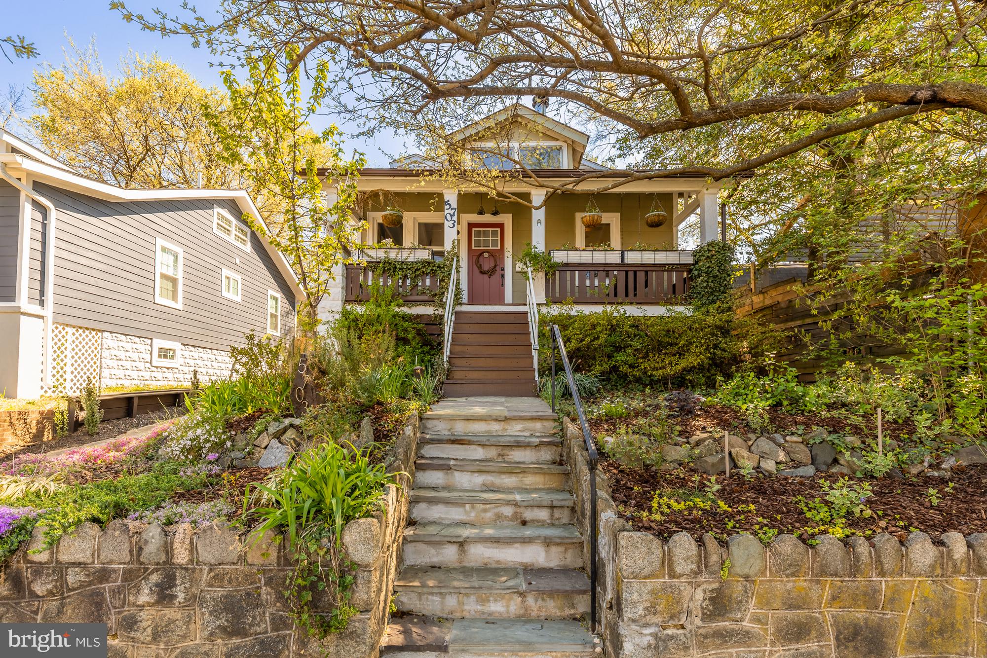 Offers appreciated by 2PM on Tuesday, April 22nd. This charming three-story bungalow in the heart of the Historic Arts District of Hyattsville offers the perfect blend of character, space, and serenity—anchored by a truly rare and unique outdoor oasis that feels like your own private retreat. Situated on a quiet, tree-lined block, the home boasts incredible curb appeal with beautifully landscaped gardens leading up to a welcoming front porch complete with a classic porch swing. Inside, soaring ceilings, hardwood floors, abundant natural light, and elegant moldings create a warm and inviting atmosphere.
The spacious living room features a striking wood stove fireplace that rises two stories, flowing seamlessly into the dining area and a well-equipped kitchen with stainless steel appliances. Step outside to a true outdoor oasis—an expansive deck and peaceful backyard retreat with ample seating, shaded canopies, gardens, ponds, and lush landscaping. A main-level bedroom with a Murphy bed and full bath offers convenience and flexibility.
Upstairs, two bedrooms include one with a built-in loft and sliding glass doors that open to a tranquil balcony, and another with vaulted ceilings and a skylight. A full bath and several storage closets complete the upper level. The finished basement adds a fourth bedroom, half bath, large recreation space, laundry, and generous storage. Driveway parking rounds out this thoughtfully maintained home just moments from shops, dining, and community events.