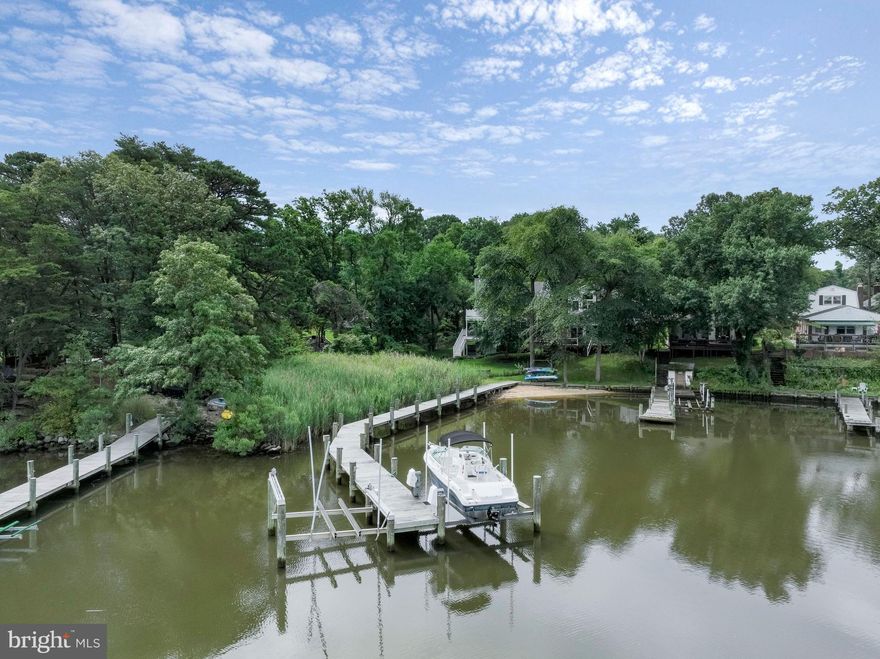 Vacation where you live!  Nestled on the shoreline of Furnace Creek , this waterfront property offers a  relaxing environment away from the hustle and bustle of everyday life. This charming home boasts 2 levels of living, large storage space under the home for water toys and yard equipment, a 2 car garage and a seamless fusion of indoor and outdoor living. The lower level of the home is dedicated to entertainment and relaxation. The spacious family room is adorned with glass sliding doors that lead to a screened-in porch, offering  views of the water and gentle breezes.  This versatile space is perfect for hosting gatherings, game nights, or simply unwinding after a day on the water.  Additionally, a stacked stone wood-burning fireplace serves as the centerpiece, providing warmth and ambiance during cozy evenings. Access to the garage, laundry room and storage are on this level.   Moving to the second floor, the heart of the home,  you'll be greeted by an open floor plan that maximizes natural light and showcases the  water views. The well-appointed kitchen seamlessly flows into the living and dining areas with access to the deck making it a perfect space for entertaining guests or simply enjoying time with family. This level also features two bedrooms, a full bath, plus a primary suite with an en suite bath boasting comfort height double vanities, sparkling granite countertop, soaking tub and separate shower with frameless door. For the boating enthusiasts, this property offers a shared pier with a boat lift, electric and water. Whether you're into fishing, crabbing, water sports, or simply enjoying leisurely cruises, this waterfront home has you covered. The outdoor amenities continue to impress with a thoughtfully designed fire pit area.   Don't miss the opportunity to make this  waterfront property your own!  Owners pay for electric at dock and neighbors pay water.  (Recent upgrades include new HVAC, flooring in hall and primary bedroom, cooktop, garbage disposal, hot water heater, rewiring of boat ramp, flooring in front of fireplace.)