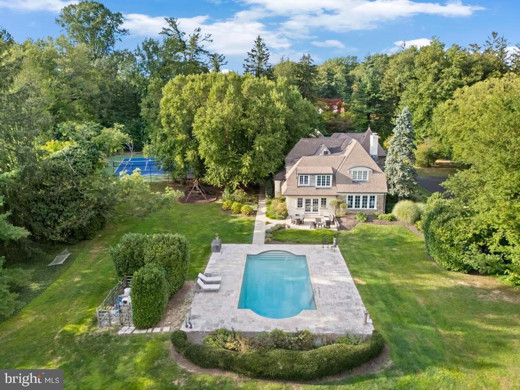 This elegant stone Tudor sits on almost three acres on one of the most coveted streets in Rydal. As you step into the turreted entrance onto the marble foyer floor, to your left is a spacious living room with a wood burning fireplace along with an adjacent sitting area overlooking the gardens. To your right is the dining room that flows through the butlers pantry and into the updated gourmet kitchen with a sub zero, granite counters, double built in ovens, and an abundance of high end cabinets with slow close drawers. Off the kitchen there is a half bath and around the corner is an expansive family room that adjoins a large playroom overlooking the pool. Upstairs there is the large primary bedroom with en suite bathroom, along with an attached dressing room with multiple closets. A second bedroom has a sitting room and also has en suite bath and the two additional bedrooms share a hall bath. Through the breezeway off of the kitchen, you will find a newly built three car garage that offers guest quarters above with a bedroom, full bath and a separate HVAC system. The grounds are magnificent! There is a beautiful salt water pool surrounded by Travertine paving There is a full size tennis and pickleball court, a slate patio that's perfect for outdoor dining, and many mature trees and hedges that provide privacy to the grounds. The location can't be beat. The property adjoins the twenty acre Crosswicks Wildlife Refuge and is minutes from Whole Foods, Trader Joes, many casual and fine dining restaurants, shopping, and Septa regional rail for an easy ride to Center City. Special homes like this don't come on the market very often. Schedule your showing today.