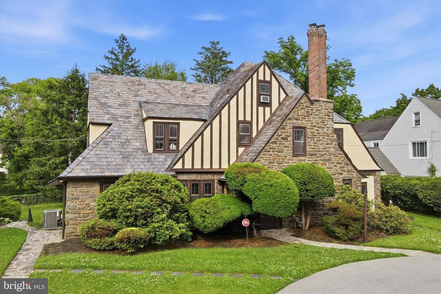 Nestled in the heart of Elkins Park, this stunning Tudor exudes timeless charm, elegant character, and an exceptional layout designed for both everyday living and unforgettable entertaining. A graceful circular driveway sets the tone as you arrive at this stately residence, welcoming you into a grand entry foyer that immediately showcases the home’s warmth and architectural beauty.
The oversized living room is truly spectacular, featuring a dramatic wood inlay ceiling, rich in detail and craftsmanship, along with a striking wood-burning fireplace that anchors the space beautifully. A step-down sitting area offers a  cozy spot for relaxation.  
Curved archways throughout the first floor add sophistication and flow, guiding you into the elegant formal dining room also with a custom wood inlaid ceiling. This spot is perfectly positioned for entertaining and connected to a thoughtfully placed first-floor office ideal for today’s lifestyle. The spacious kitchen offers both functionality and charm with a galley-style workspace and a sunny eat-in area perfect for casual dining.
Upstairs you will find four perfectly sized bedrooms and two full baths  (one is a Jack and Jill and the other is in the hallway). The third floor offers two small bedrooms and a full bath (which  is unfinished and therefore not currently operable)
Large unfinished basement with entrance to a very oversized two car garage . The back yard is level and expansive, lending itself to a football game or a garden party!!!! Enjoy the view from the deck off of the kitchen which provides steps leading down to the backyard .
This property uses an easement to access the driveway next door (to the left of the property) in order to pull around to the back driveway.  
This exceptional Tudor is filled with character, warmth, and incredible entertaining spaces, and a rare opportunity to own a truly distinctive home in one of the area’s most desirable neighborhoods.