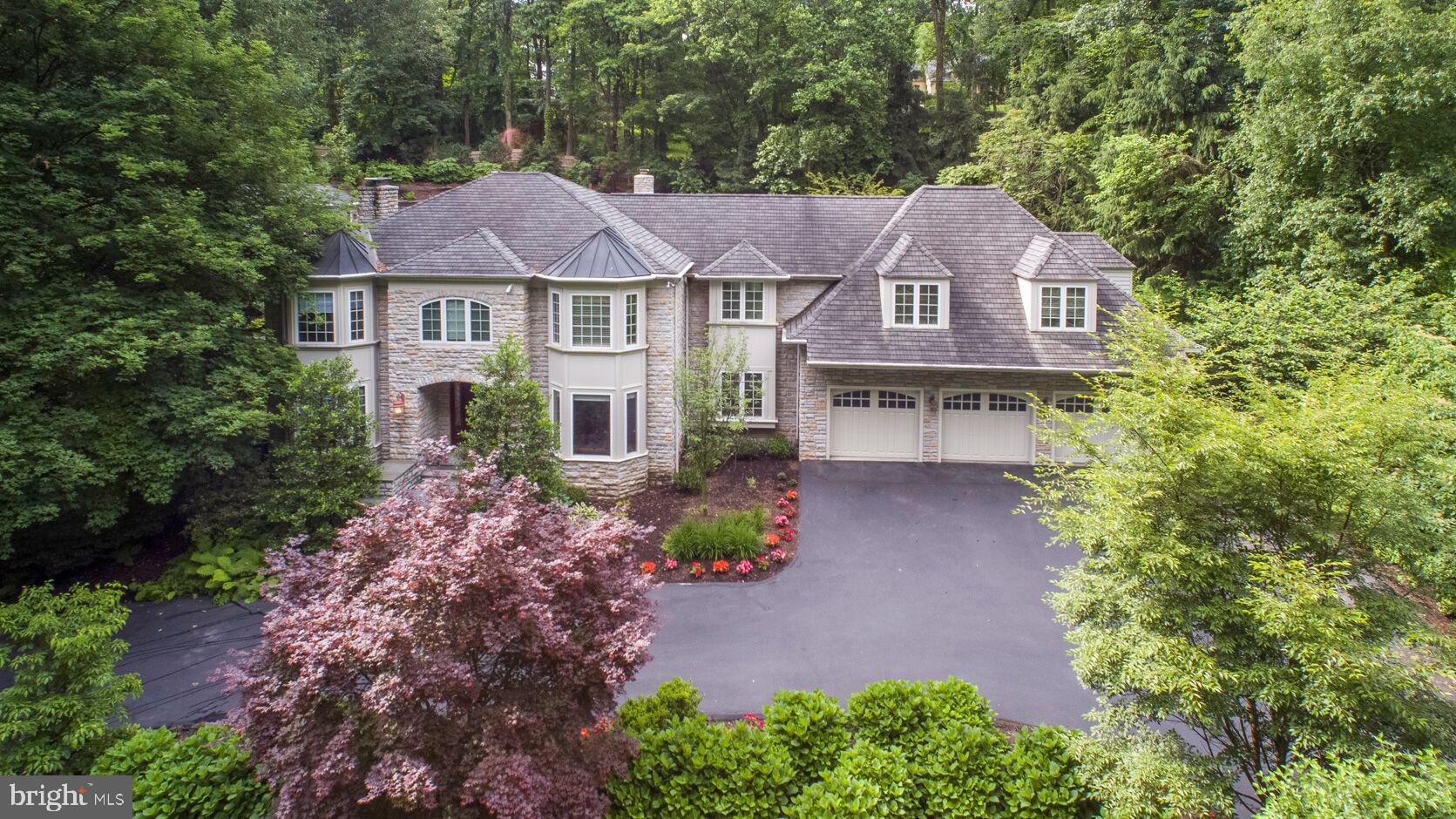 Located on a quiet cul-de-sac in Villanova, this modern, stone colonial home has hardwood floors, circular staircase, crown molding framing the entryways, and natural light flooding through every room. A seamless transition through the dining room, highlighted by custom millwork, takes you through the well-appointed butler s pantry boasting its own dishwasher, SS sink, glass front cabinets, cherry wood millwork and tumbled marble backsplash. The gourmet chef caliber kitchen has a Viking suite of double wall ovens, 48 inch built-in refrigerator/freezer, 6-burner gas cooktop and griddle, warming drawer, separate ice-maker, an abundance of storage and heated floors is anchored by a large granite island accented with cherry wainscoting. A comfortable, spacious breakfast area is open to the family room affording a view of the resort style backyard that awaits you and your family to enjoy a vacation at home. A waterfall can be seen and heard while enjoying every meal. A home office sits off of the kitchen tastefully designed to suit even the most discriminating professional. The warm family room extends out to an entertainment area with a custom designed bar area complete with 2 built-in keg drawers, dishwasher, Uliner ice-maker, refrigerator & wine cave. Completing the 1st floor is a lovely gathering room with French doors at both ends that can be used as a 2nd office, library or den. On the 2nd floor is the master suite with 3 large walk-in closets/dressing areas, custom designed built-in cherry cabinetry w/ entertainment center & fireplace. The spa-like master bath has an oversized Jacuzzi tub, 3 separate granite-topped vanities , frameless glass enclosed shower and separate water closet. Five additional bedrooms all with private baths and walk-in closets complete the 2nd floor which has stunning views of the palatial heated salt water pool, spa and pool house (with the waterfall as a backdrop) , professional grade outdoor bar and entertainment area (w/ 2 angled, mounted tv s ,included) & kitchen outfitted w/ a Lynx grill, 2 refrigerator drawers, ice maker & all Perlick appliances. The stone constructed pool house comes complete w/kitchen, W/D, powder room & tile w/slate-clad oversized, shower. All LED lit at night w/ a 30 foot fireplace to enjoy throughout the year. The basement level w/ 908 additional sq. ft boasts a private yoga studio, fitness center, powder room, storage areas & egress out to the backyard. Attached 3-bay garage has epoxy coated flooring. Whole-house generator keeps all of the systems running, even during the worst of storms.